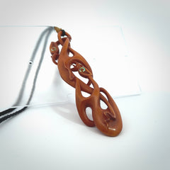 A one off beautiful piece of carved art. Hand carved for us by Yuri Terenyi and is a double manaia pendant. This is a wonderful ethnic bone pendant designed to be worn. It has been stained by a homemade tea dye in a bright gingery brown colour and we have hand plaited an adjustable cord in black with a burnt gold floret popper.