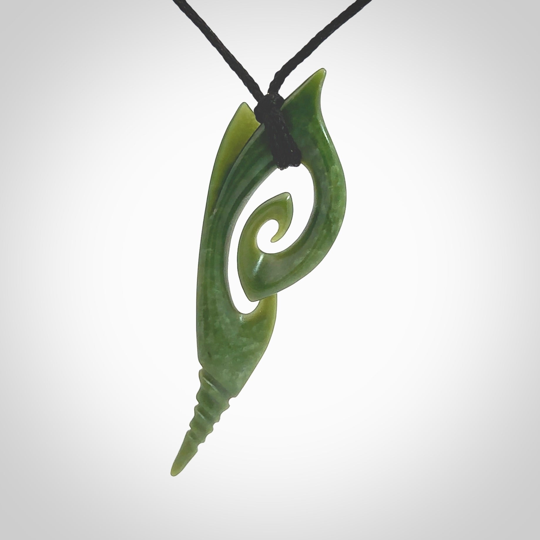 This photo shows a koru pendant carved from New Zealand Jade. The artist, Shaun Gardiner, has carved this beautifully. We provide this piece with an adjustable black cord. This is a fantastic work of art, we have one only.