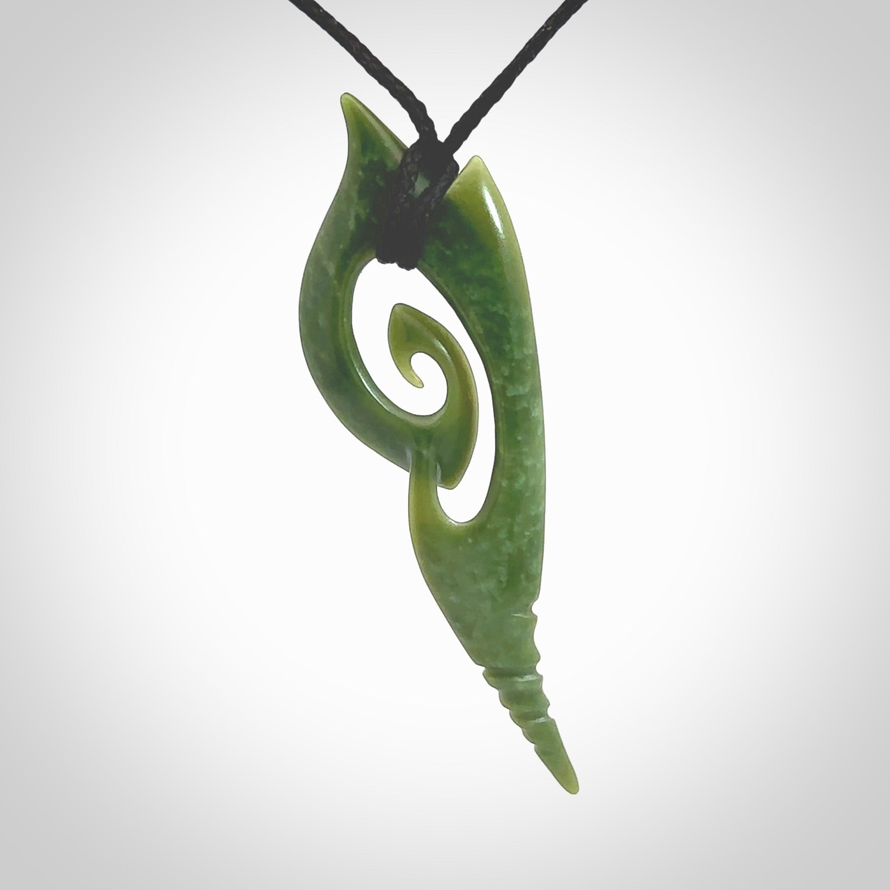 This photo shows a koru pendant carved from New Zealand Jade. The artist, Shaun Gardiner, has carved this beautifully. We provide this piece with an adjustable black cord. This is a fantastic work of art, we have one only.