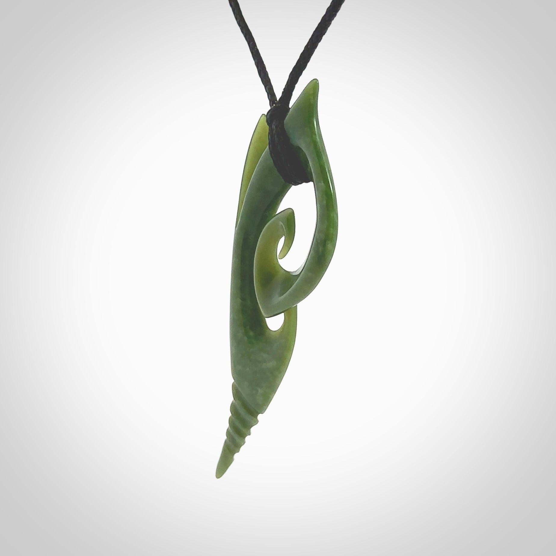 This photo shows a koru pendant carved from New Zealand Jade. The artist, Shaun Gardiner, has carved this beautifully. We provide this piece with an adjustable black cord. This is a fantastic work of art, we have one only.