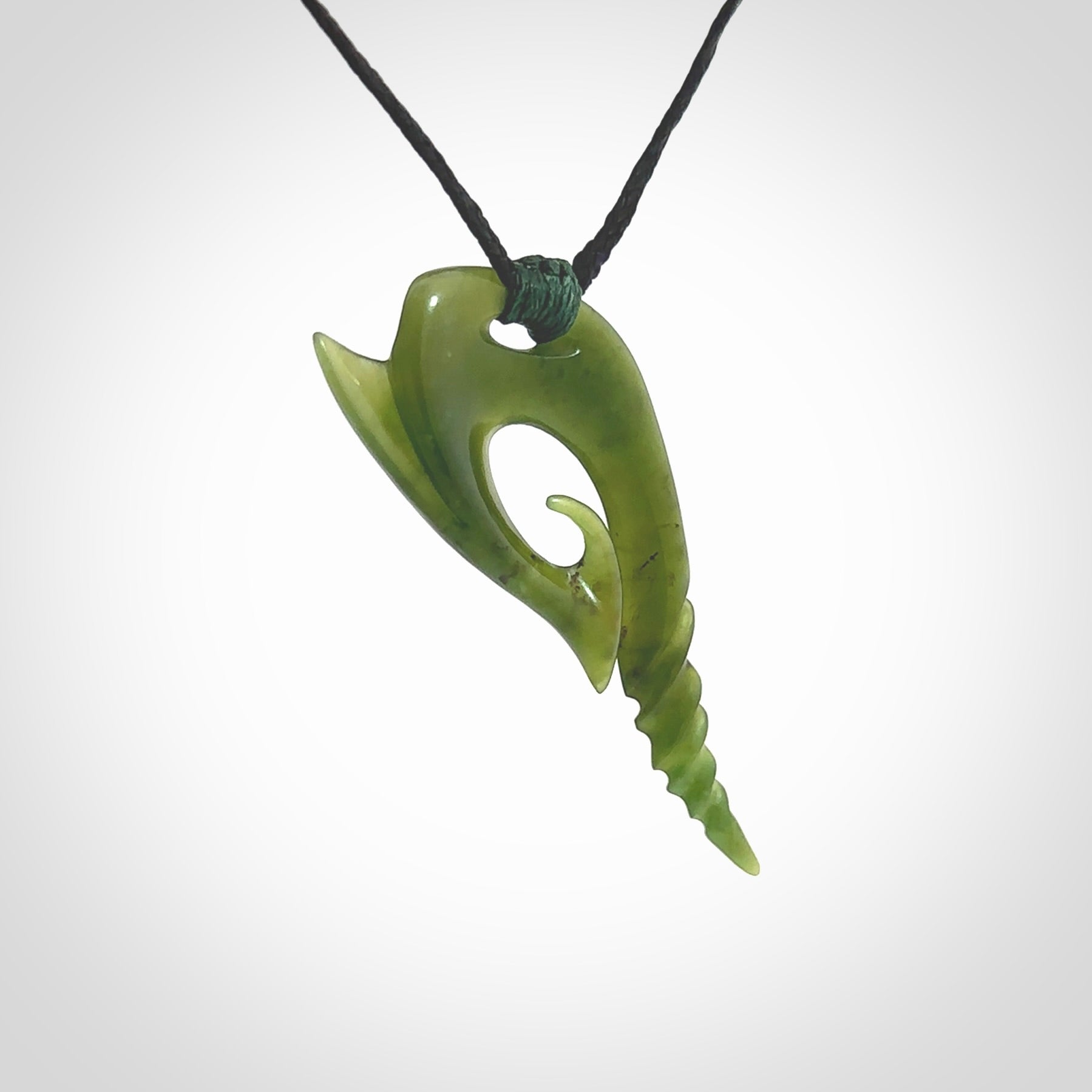 This photo shows a contemporary koru pendant carved from New Zealand Jade. The artist, Shaun Gardiner, has carved this beautifully. We provide this piece with an adjustable black cord. This is a fantastic work of art, we have one only.