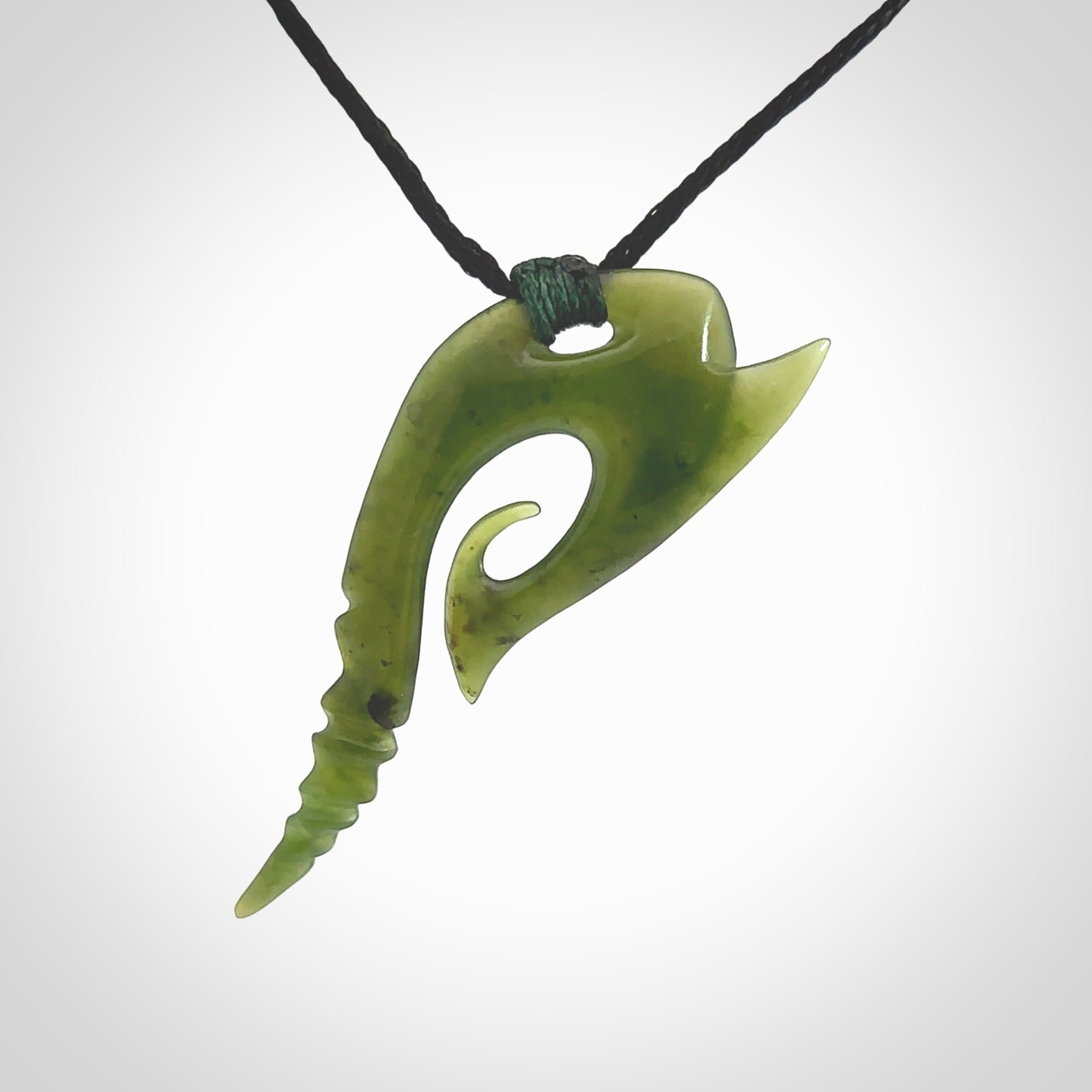 This photo shows a contemporary koru pendant carved from New Zealand Jade. The artist, Shaun Gardiner, has carved this beautifully. We provide this piece with an adjustable black cord. This is a fantastic work of art, we have one only.