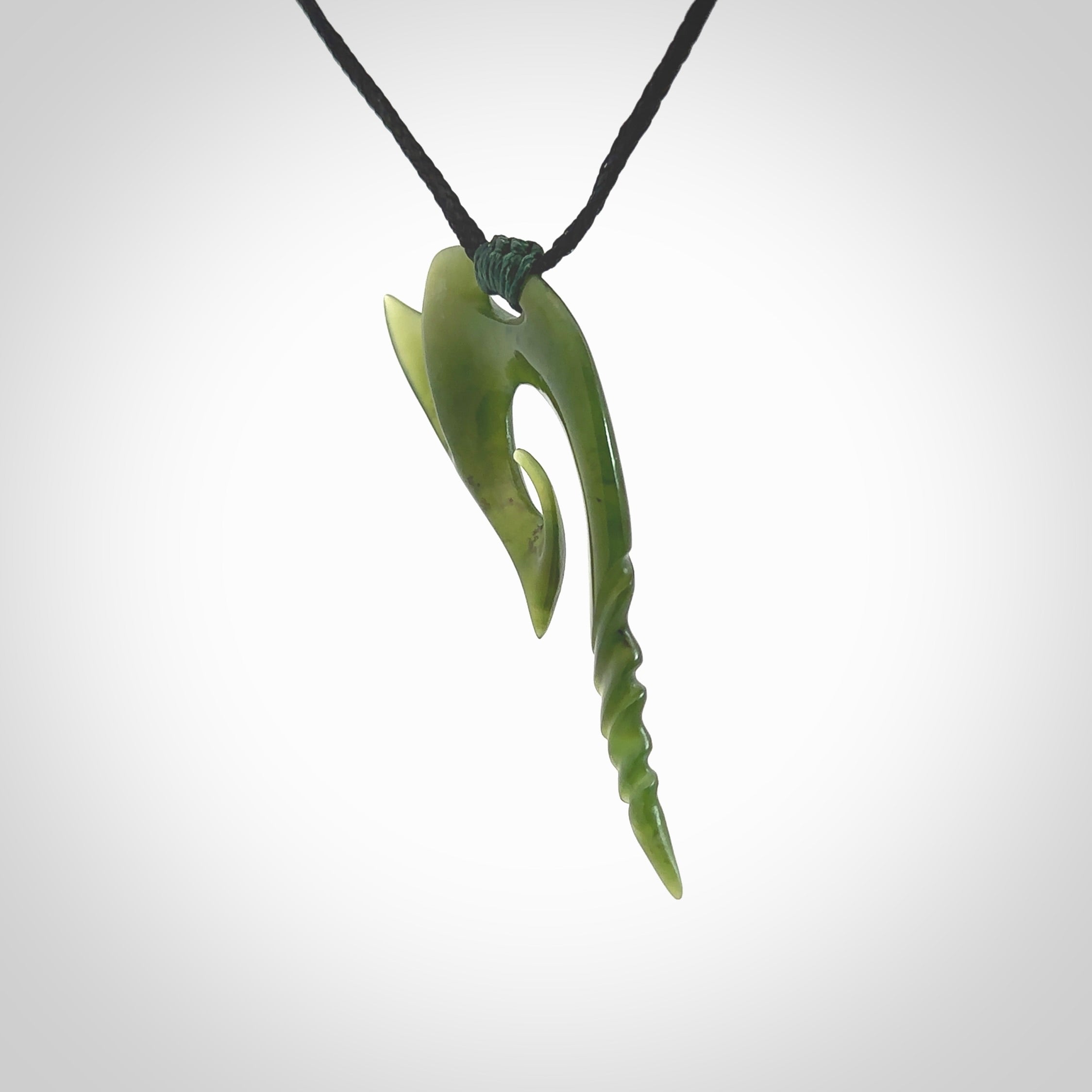 This photo shows a contemporary koru pendant carved from New Zealand Jade. The artist, Shaun Gardiner, has carved this beautifully. We provide this piece with an adjustable black cord. This is a fantastic work of art, we have one only.