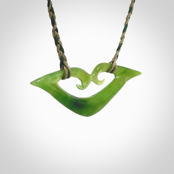 This photo shows a koru pendant carved from New Zealand Jade. The artist, Shaun Gardiner, has carved this beautifully. We provide this piece with a fixed length cord in a two toned green colour. This is a fantastic work of art, we have one only.