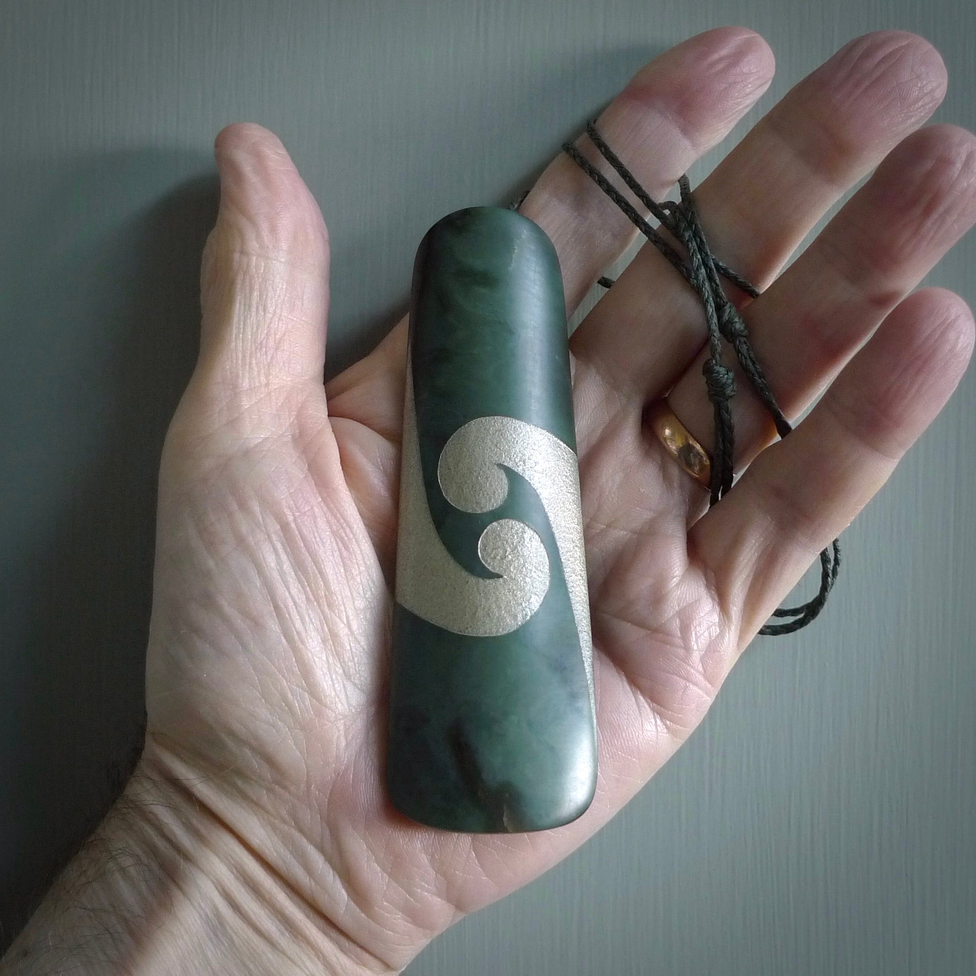 This photo shows a large jade drop shaped pendant. It a a lovely, colourful Inanga jade. The cord is a green colour and is adjustable in length. One only large, contemporary drop necklace from Jade, by Rueben Tipene.