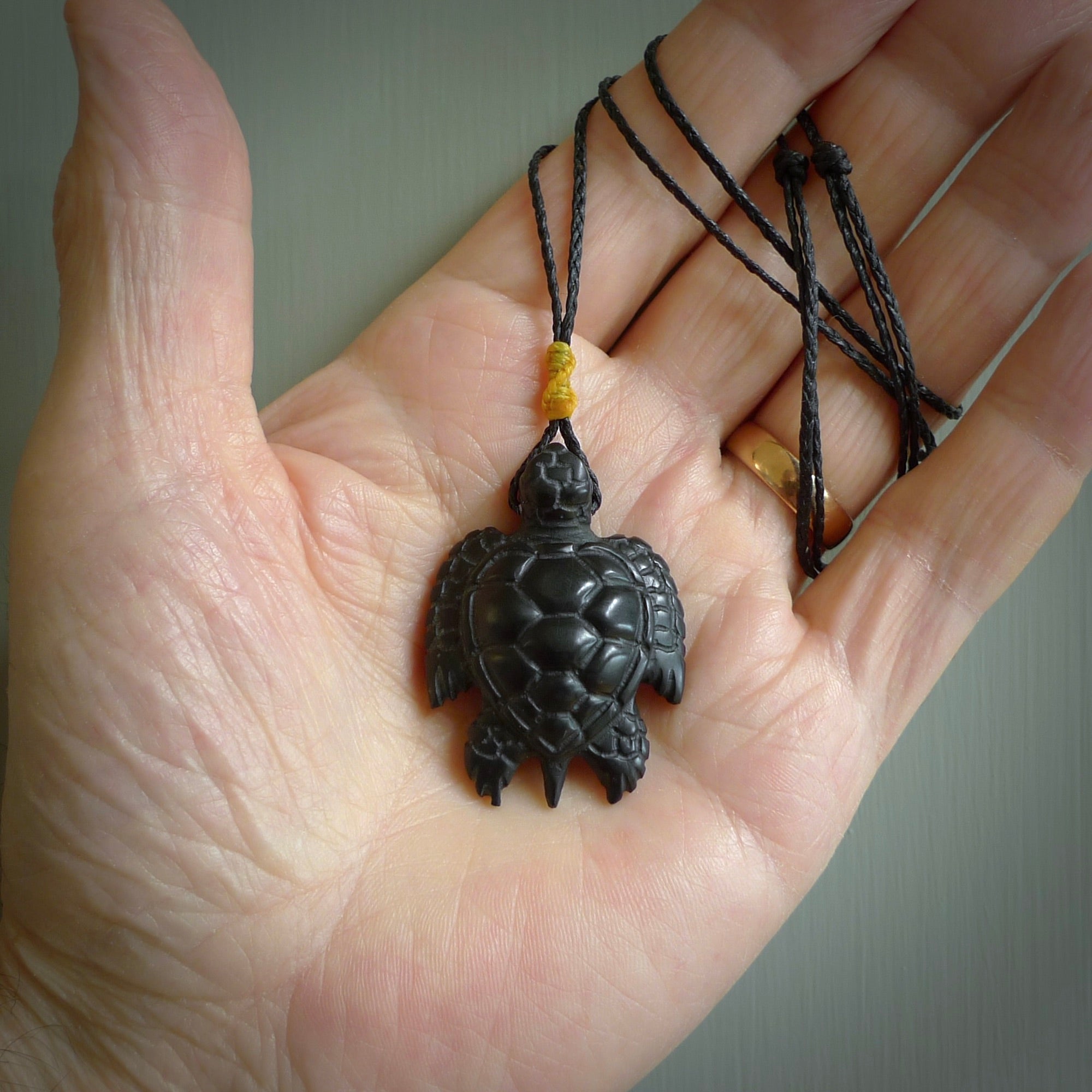 This picture shows a hand carved black jade turtle pendant. It is polished to a soft shine and has quite a lot of detail carved into the jade. The cord is a hand plaited black, waxed polyester. Carved by NZ Pacific.