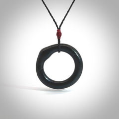 This picture shows a hand carved black jade circle pendant with sterling silver inlay. It is suspended from an adjustable Black cord. Delivery is free worldwide.