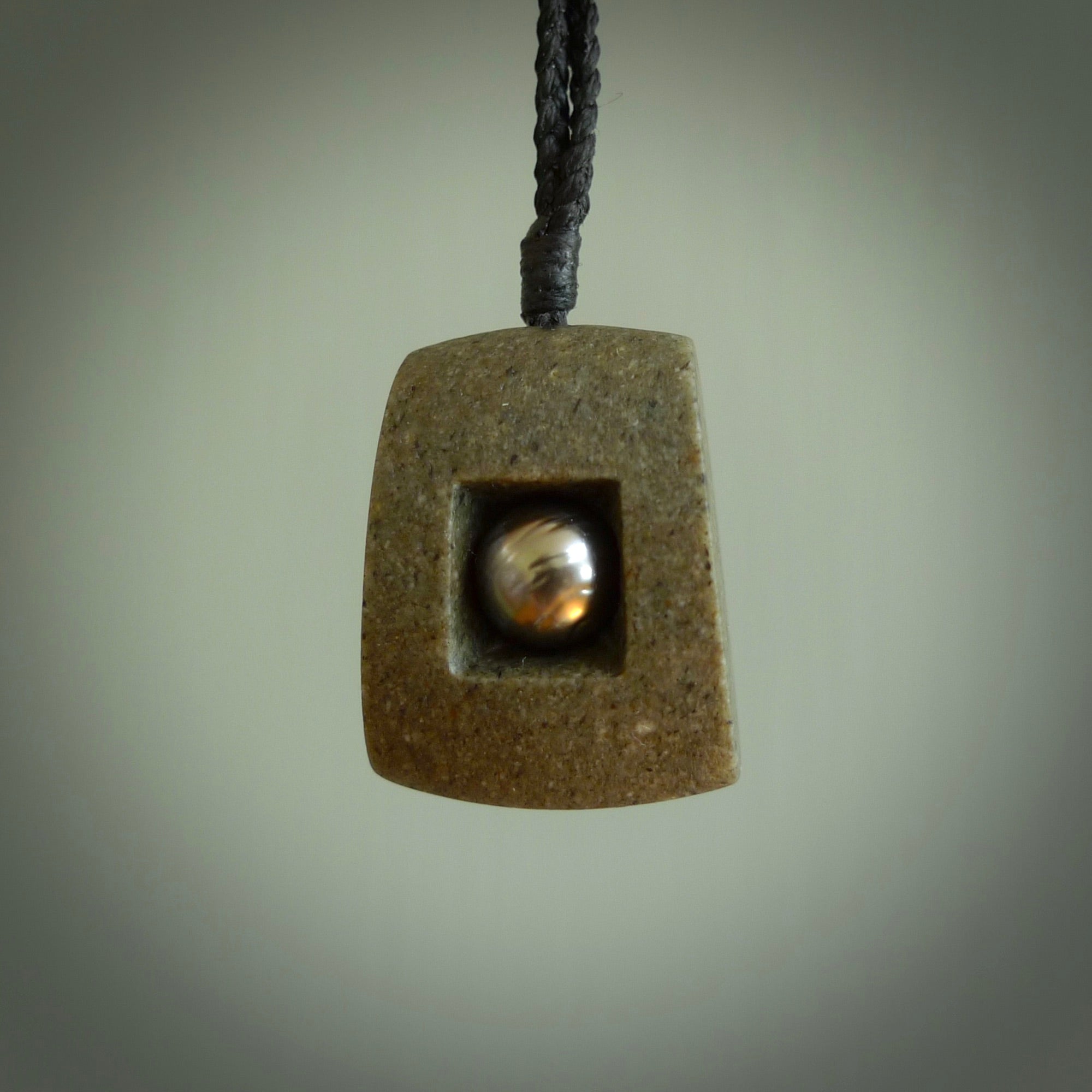 Greywacke stone pendant with Black Pearl insert. Hand carved by Rhys Hall for NZ Pacific. Handmade contemporary jewellery for sale online.