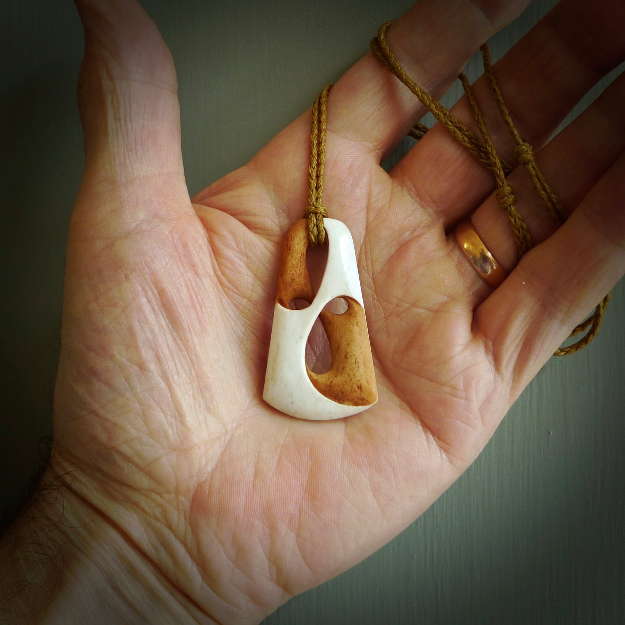 A hand carved bone contemporary, intricate, twist pendant. The cord is a tan colour and is adjustable. A medium sized hand made contemporary necklace by New Zealand artist Tonijae Brockway. Tonijae has stained parts of the bone which really add to the dimension of this pendant. One off work of art to wear.