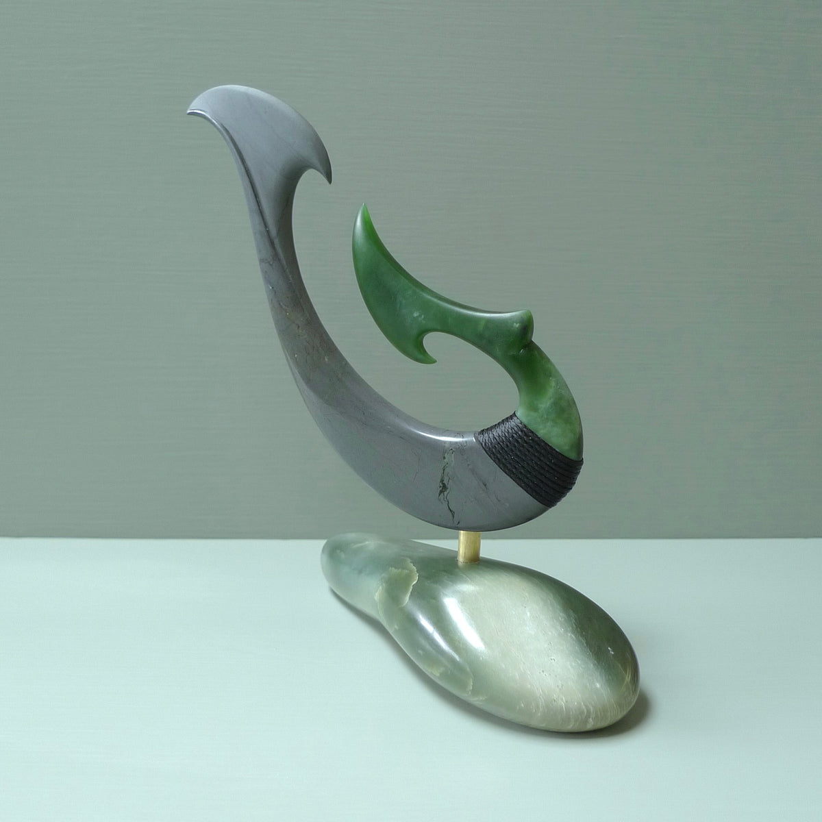 Hand carved large New Zealand Jade and Argillite Matau, hook carving displayed in a New Zealand Inanga Pounamu stand sculpture. Hand carved here in New Zealand by Kerry Thompson. This is a 'one only' sculpture, a beautiful display piece.