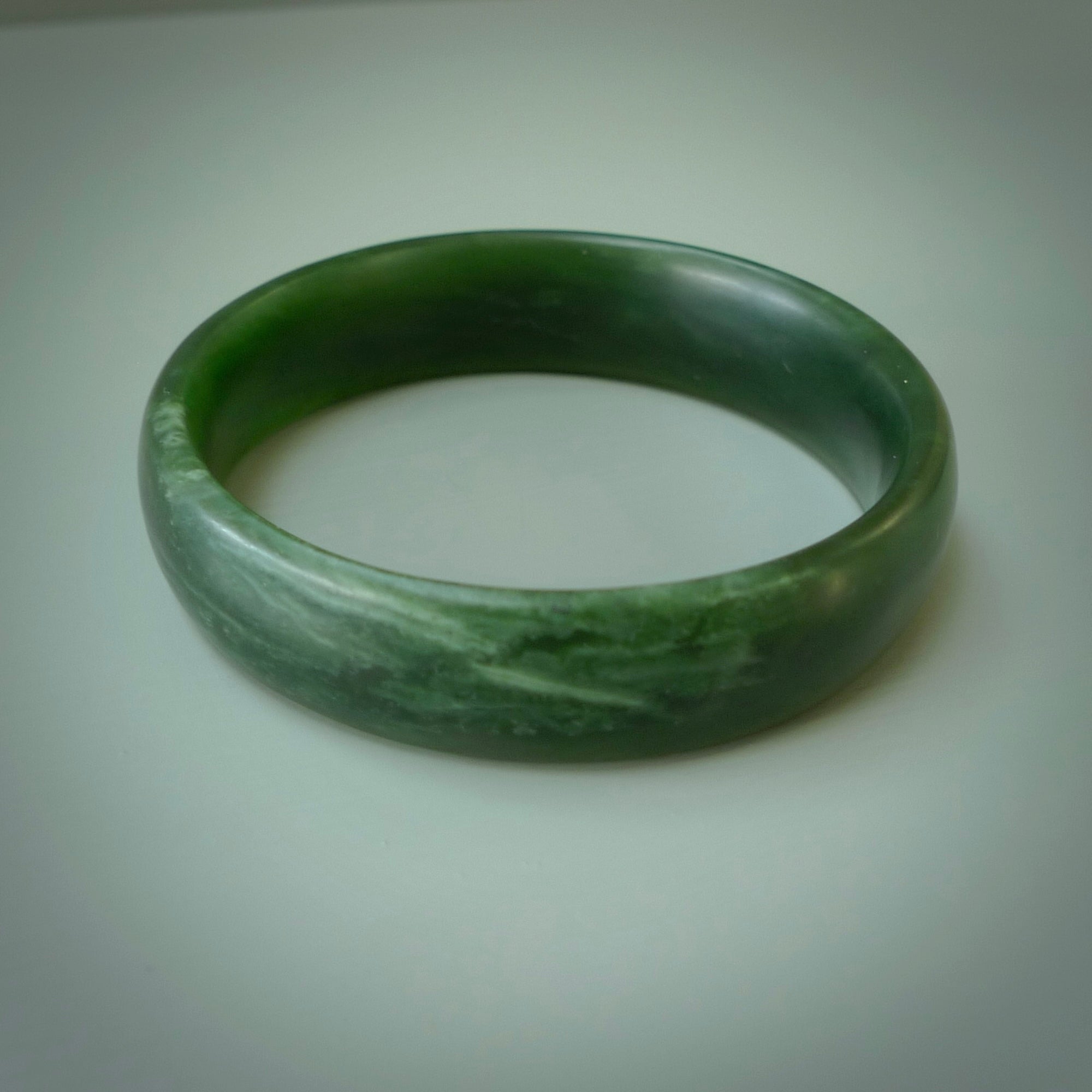 Hand carved New Zealand Jade bangle with matte finish, by Ric Moor. This is a spectacular one off, bracelet hand made in New Zealand from gorgeous Jade. Unique art to wear, delivered in a woven kete pouch. Real New Zealand Jade. Outstanding craftsmanship by New Zealand Master Carver Ric Moor.