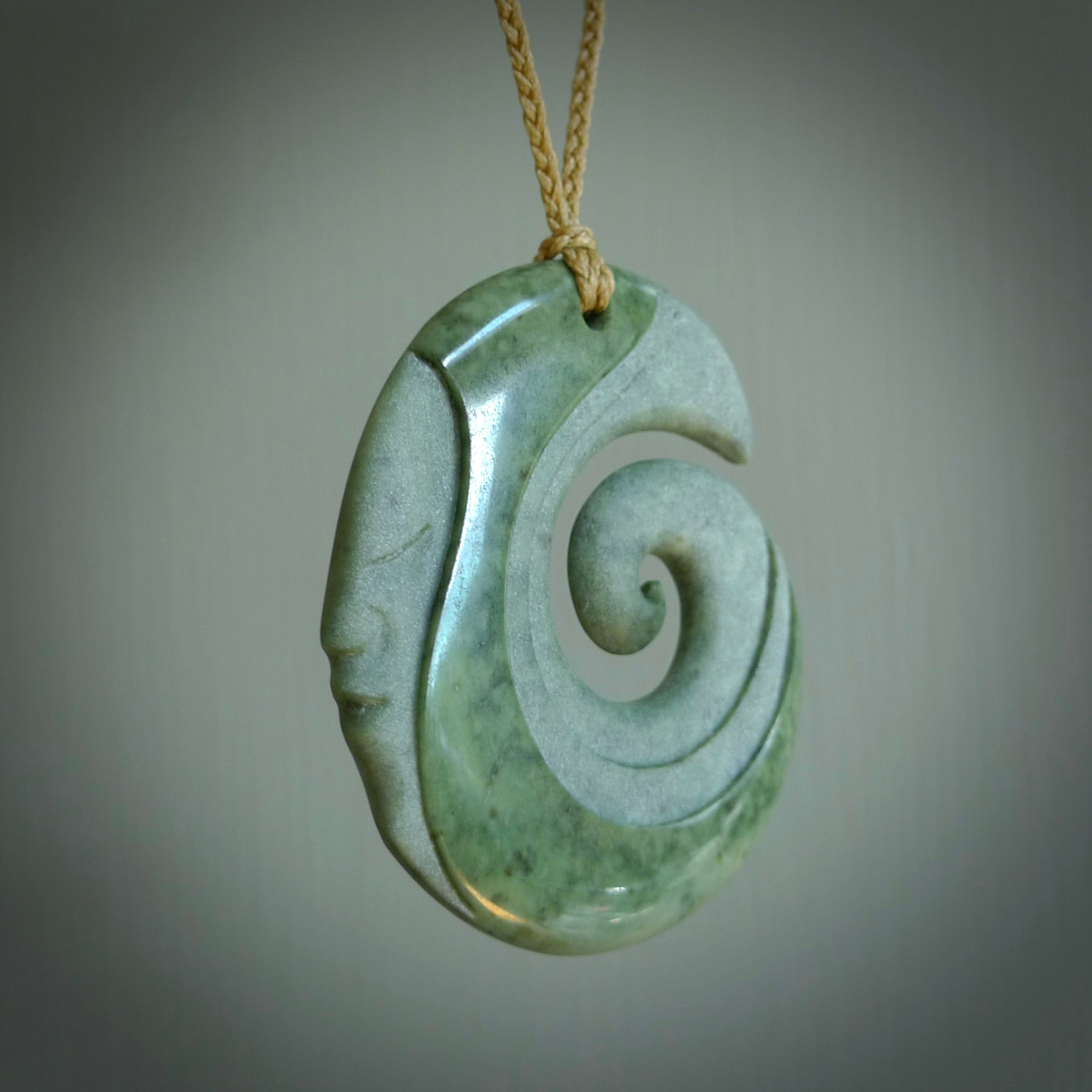 A hand carved koru with face pendant from New Zealand Pounamu, Jade. The cord is Tan and is adjustable. A large hand made Koru necklace by New Zealand artist Kerry Thompson.