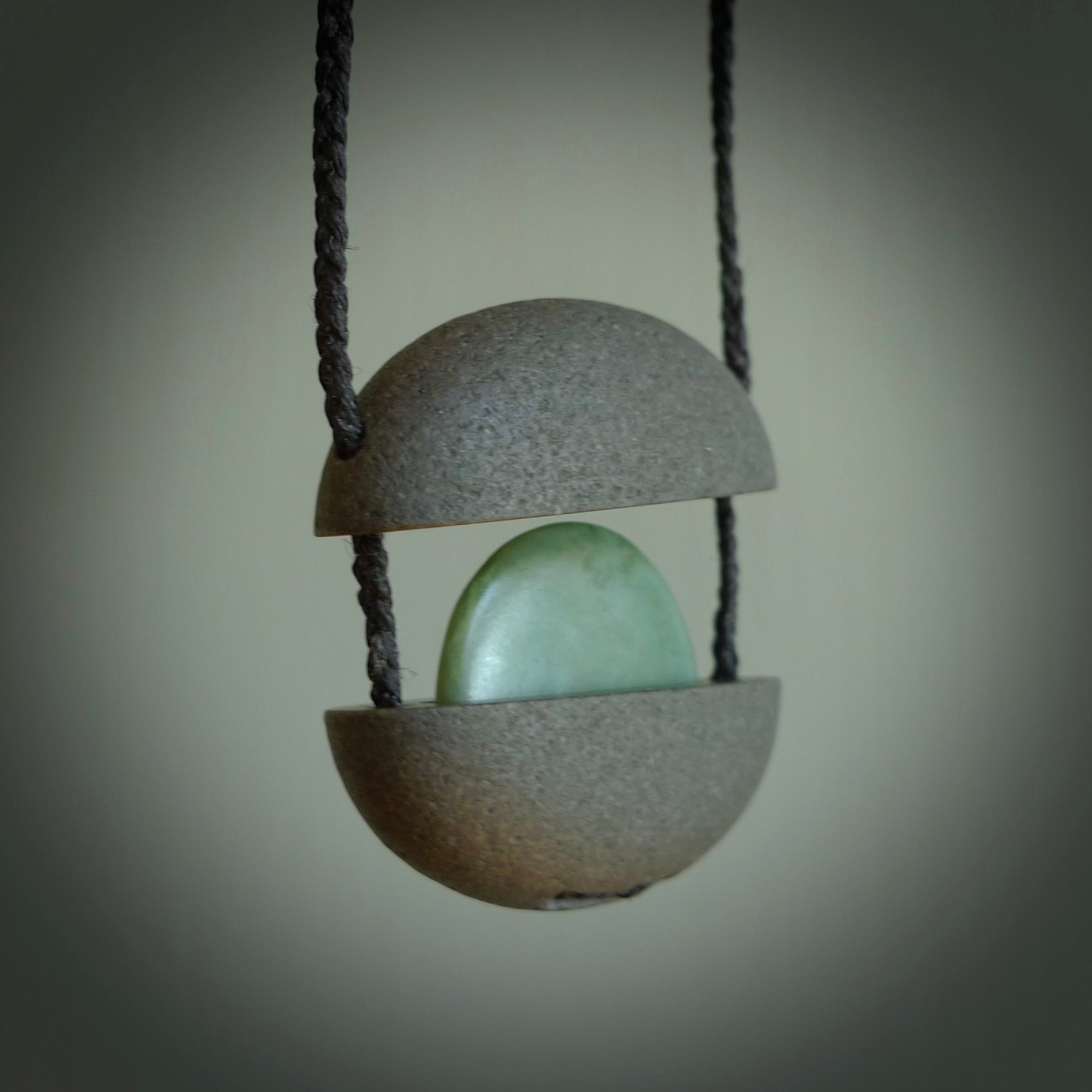 Greywacke stone pendant with New Zealand Inanga Pounamu insert. Hand carved by Rhys Hall for NZ Pacific. Handmade contemporary jewellery for sale online.