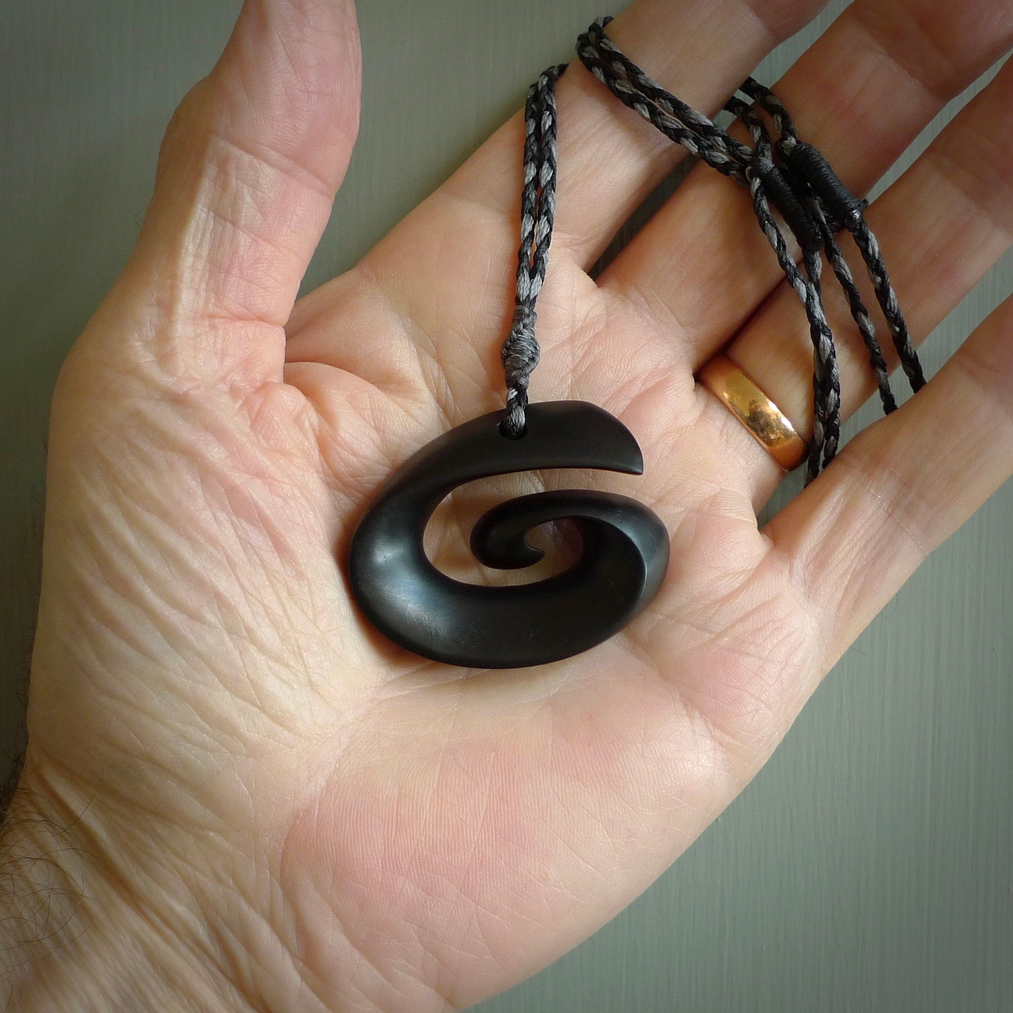 A hand carved medium sized Black Jade Koru necklace. The cord is a black colour and is a fixed length . A medium sized hand made hook necklace by New Zealand artist Kerry Thompson. One off work of art to wear.