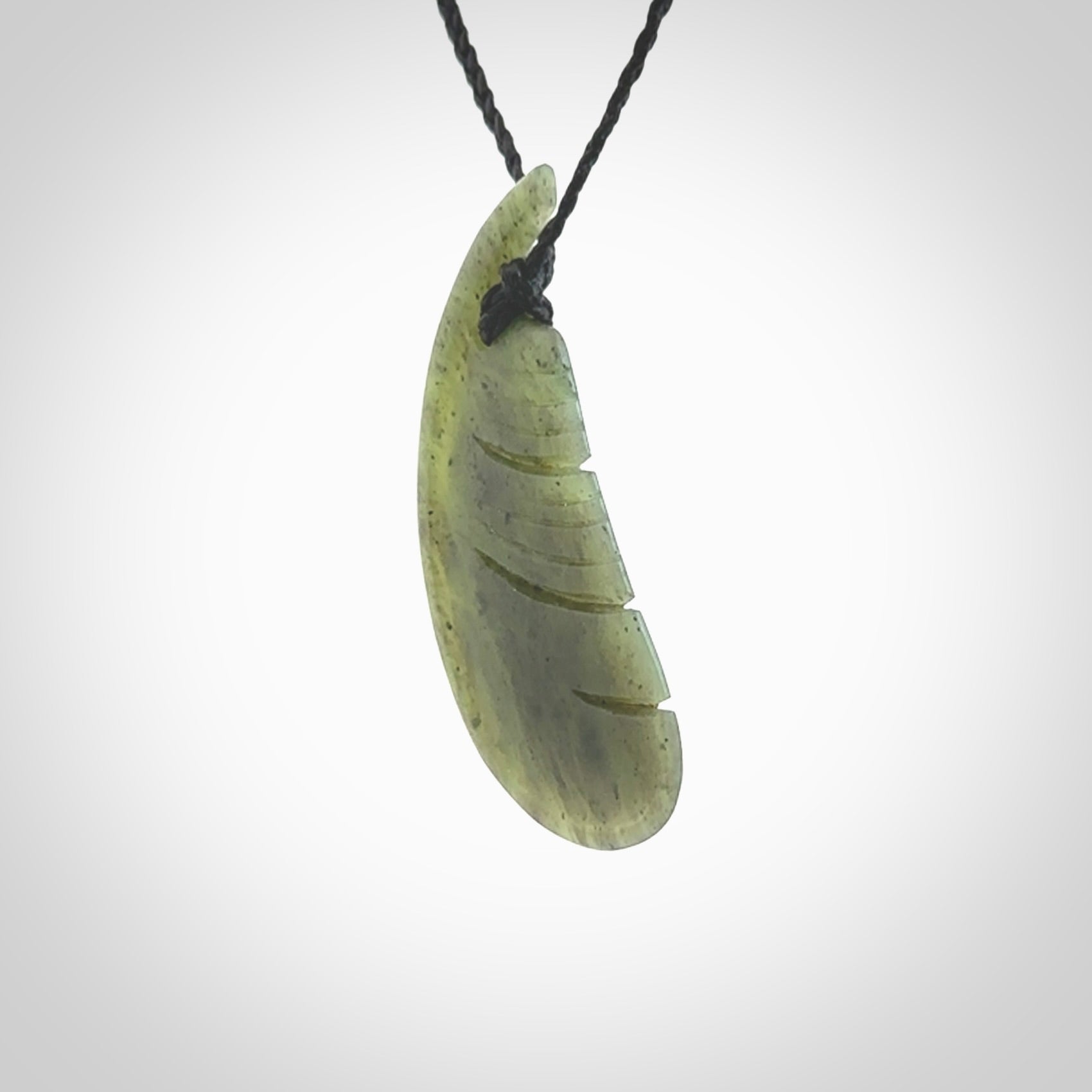 A hand carved New Zealand Totoweka Jade feather necklace. The cord is a black colour and is an adjustable length. Hand made Jade feather necklace by New Zealand artist Kerry Thompson. One off work of art to wear.