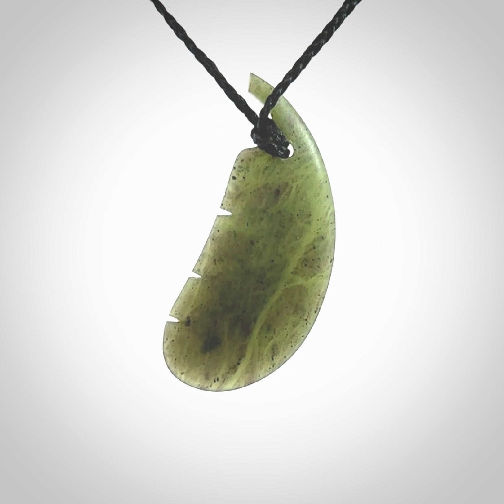 A hand carved New Zealand Totoweka Jade feather necklace. The cord is a black colour and is an adjustable length. Hand made Jade feather necklace by New Zealand artist Kerry Thompson. One off work of art to wear.