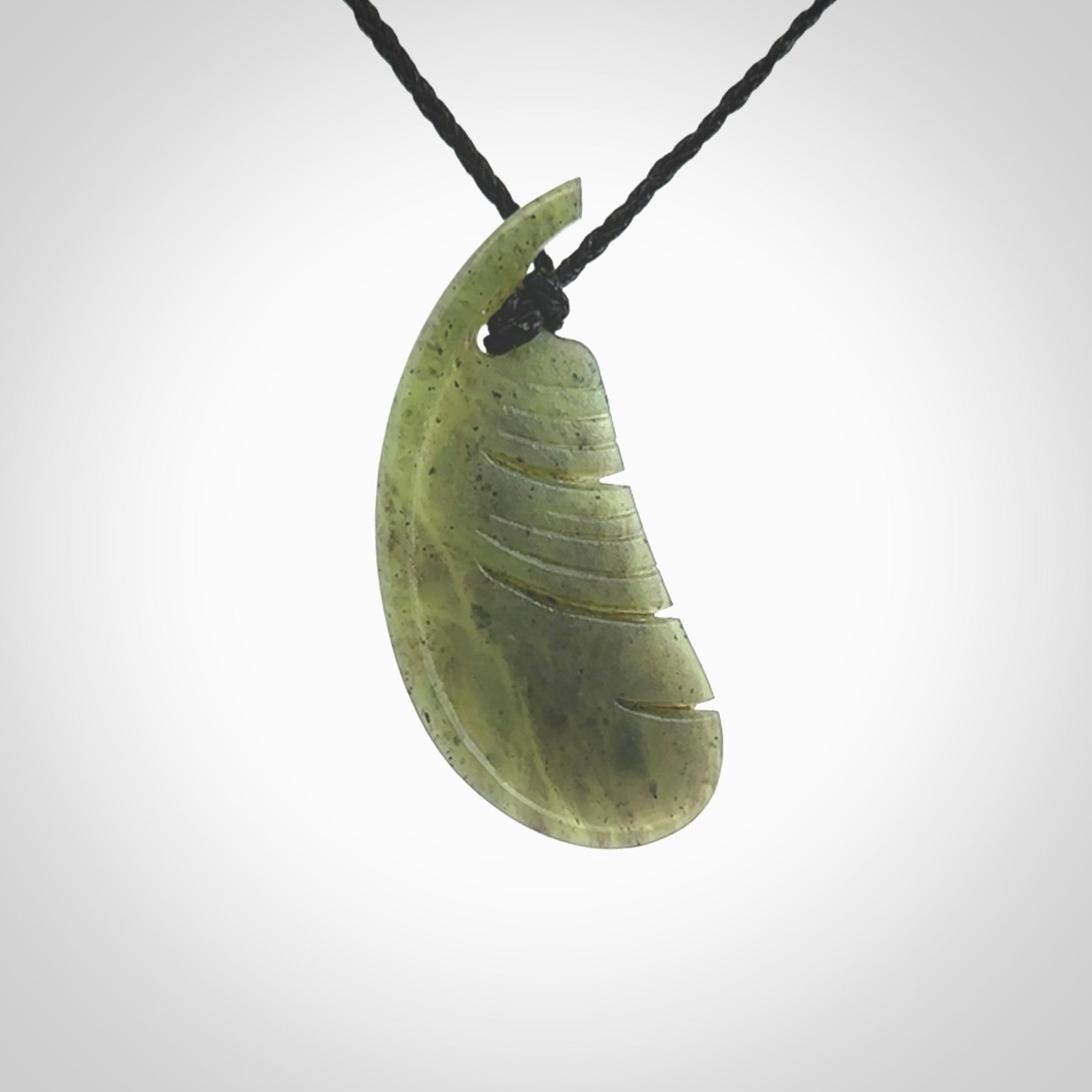 A hand carved New Zealand Totoweka Jade feather necklace. The cord is a black colour and is an adjustable length. Hand made Jade feather necklace by New Zealand artist Kerry Thompson. One off work of art to wear.