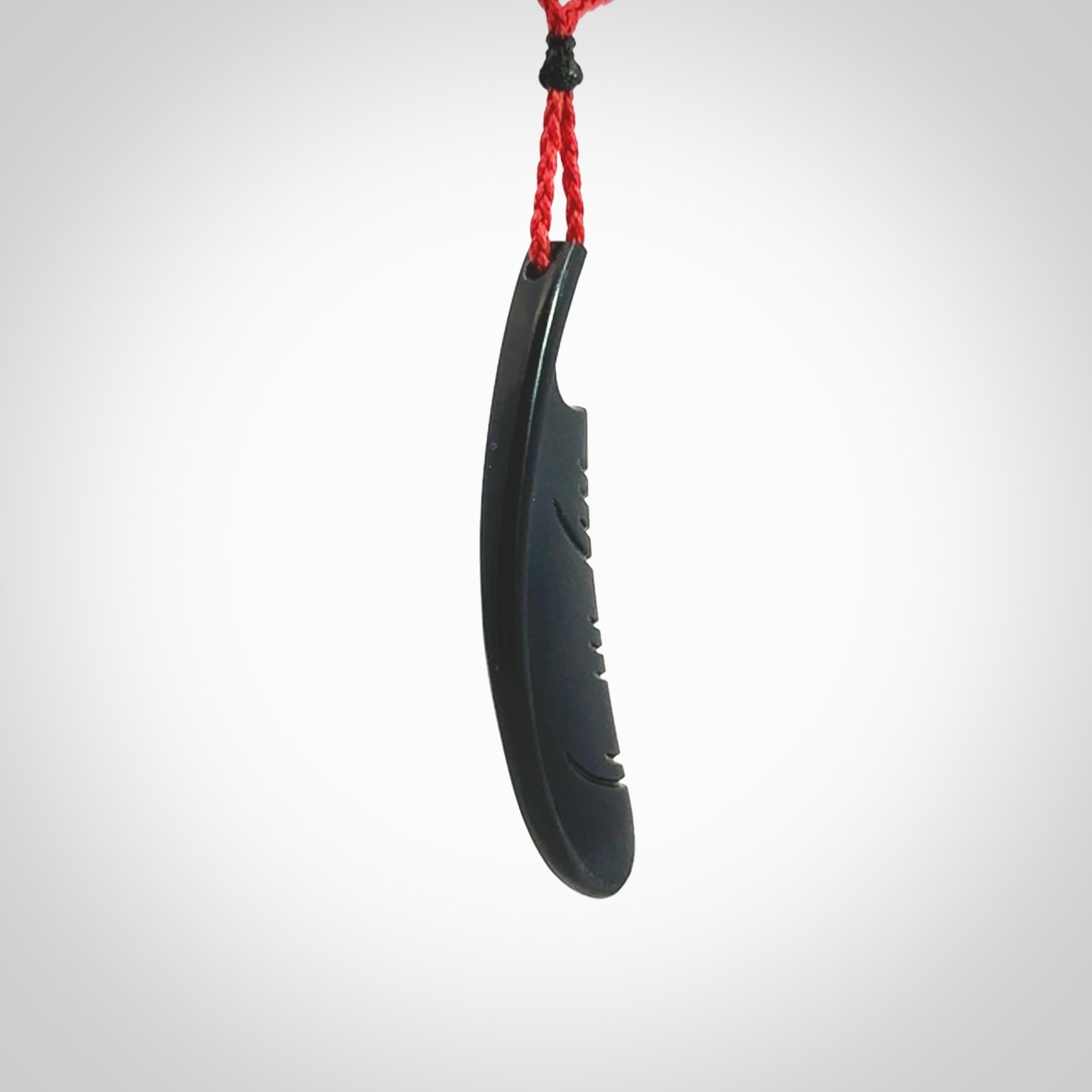 A hand carved large Wyoming Black Jade feather necklace. The cord is a red colour and is an adjustable length. A large sized hand made Black Jade feather necklace by New Zealand artist Kerry Thompson. One off work of art to wear.