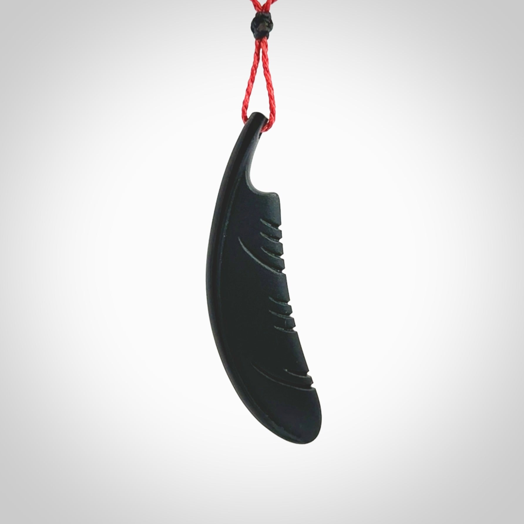 A hand carved large Wyoming Black Jade feather necklace. The cord is a red colour and is an adjustable length. A large sized hand made Black Jade feather necklace by New Zealand artist Kerry Thompson. One off work of art to wear.