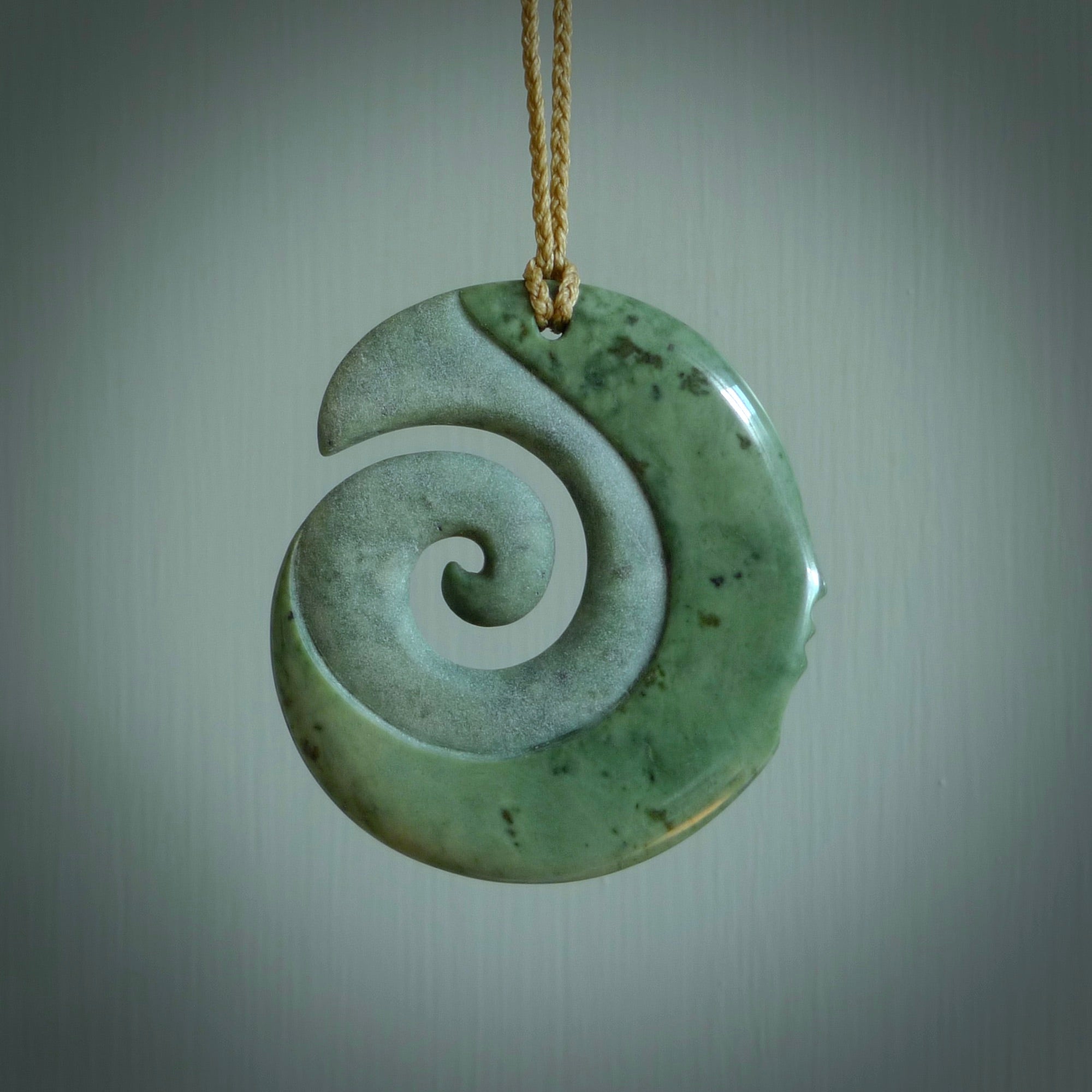 A hand carved koru with face pendant from New Zealand Pounamu, Jade. The cord is Tan and is adjustable. A large hand made Koru necklace by New Zealand artist Kerry Thompson.