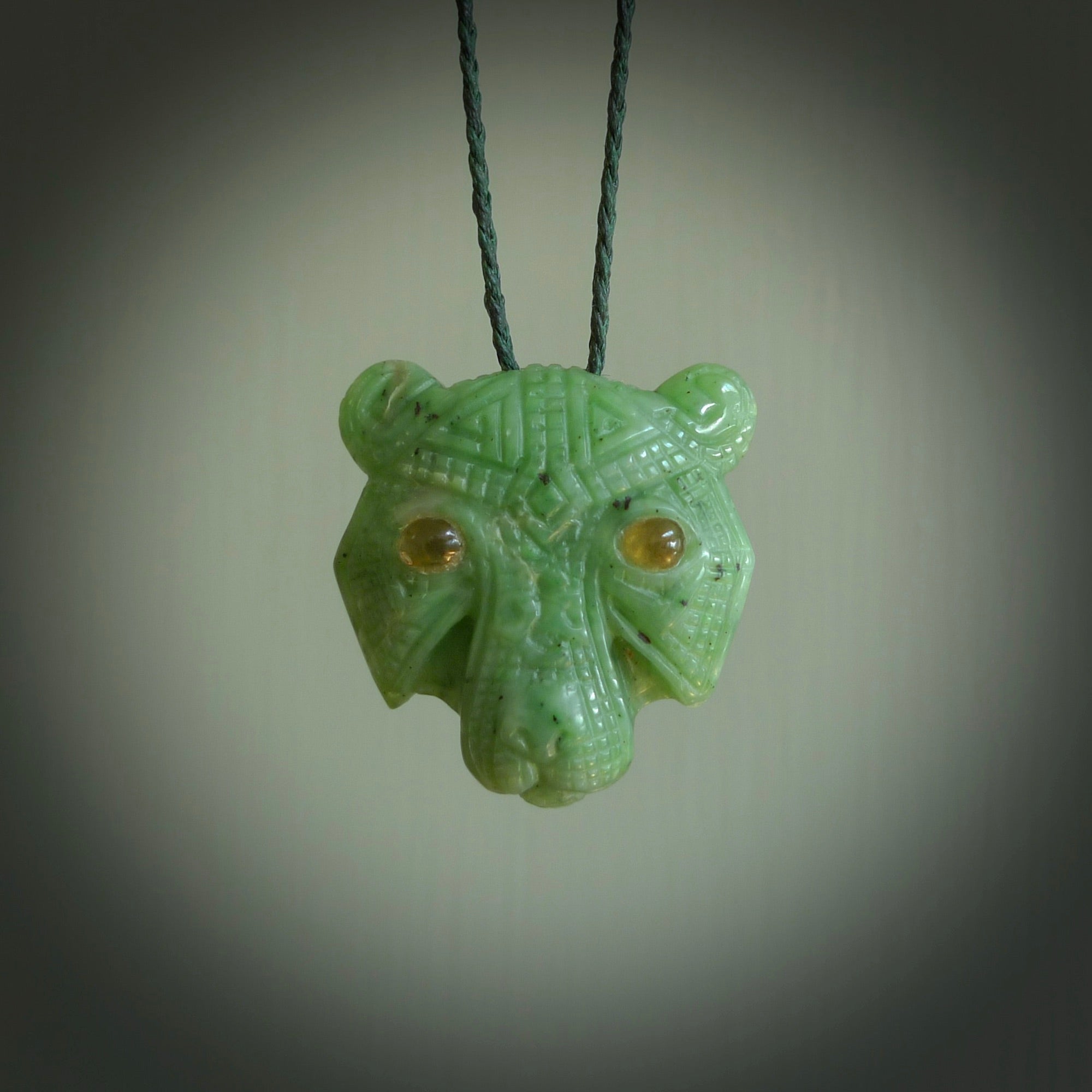 This picture shows a tiger pendant that we designed in Jade stone with Amber inlay eyes. It is a tiger head that is carved in detail. A really attractive and eye-catching piece of handmade jewellery. The cord is hand plaited braid in green and the length can be adjusted.