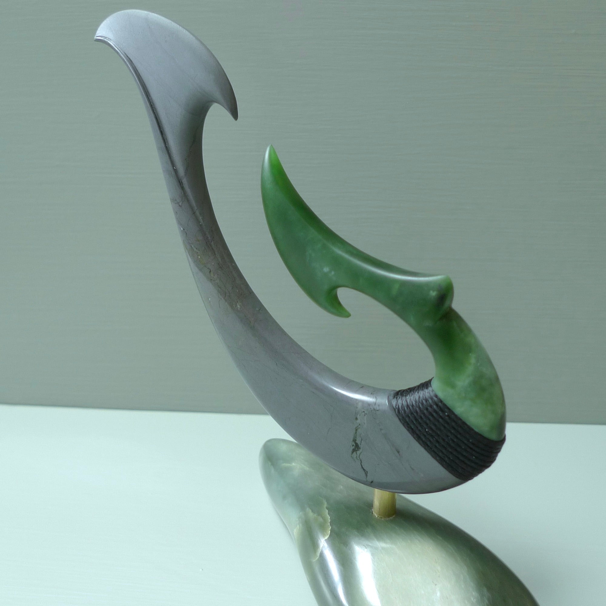 Hand carved large New Zealand Jade and Argillite Matau, hook carving displayed in a New Zealand Inanga Pounamu stand sculpture. Hand carved here in New Zealand by Kerry Thompson. This is a 'one only' sculpture, a beautiful display piece.