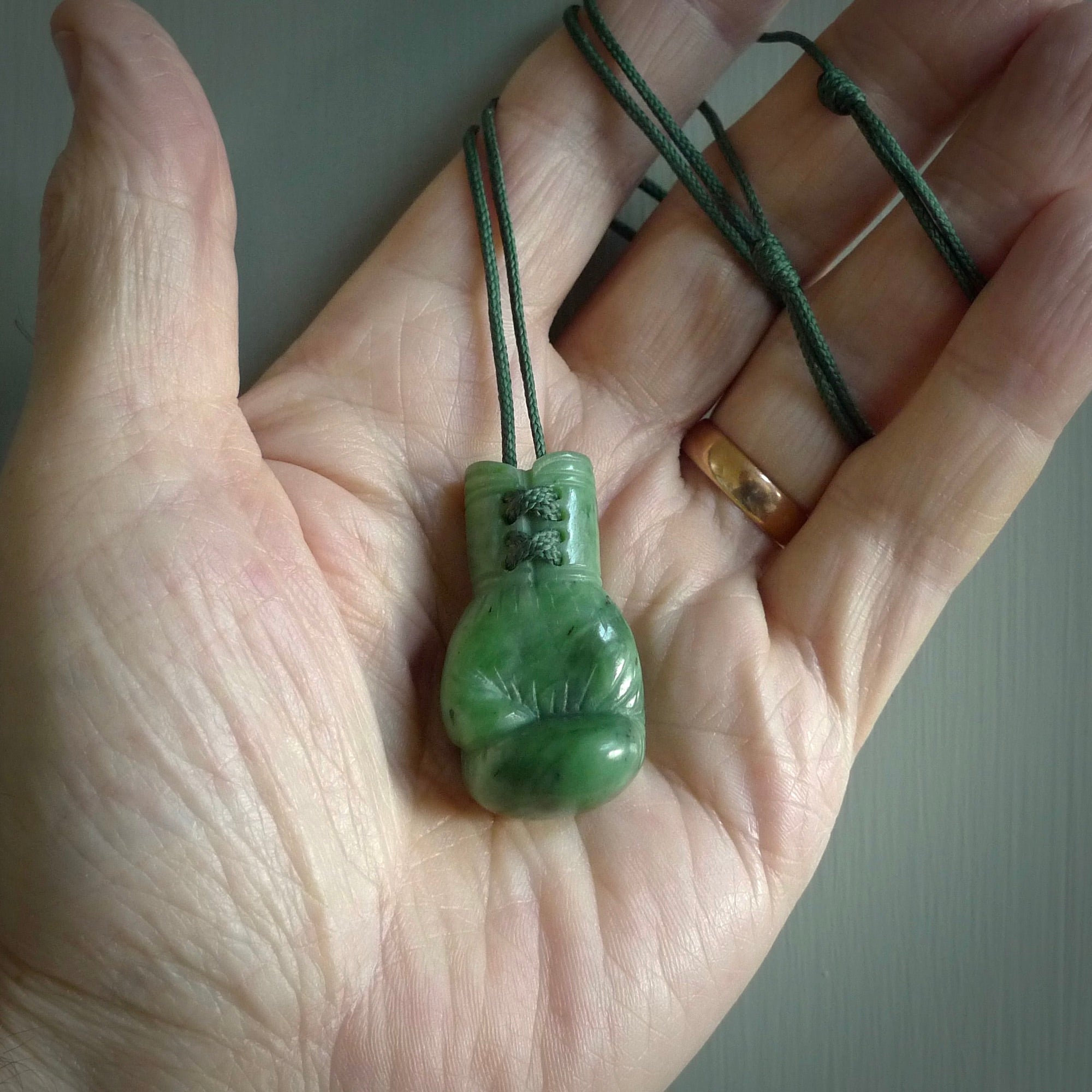 Hand carved boxing glove made from New Zealand Jade. The cord is adjustable so that you can wear this where it suits you best. We have bound these with a Oat coloured cord which contrasts with the green of the jade glove. The cost of shipping worldwide is included in the price.