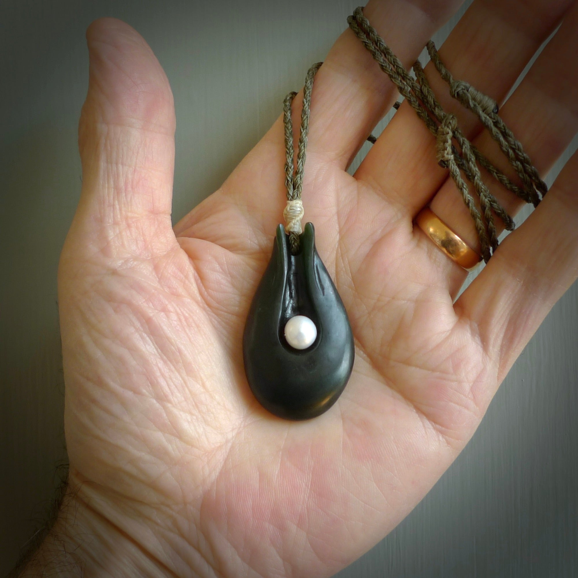 This is a unique contemporary drop pendant, hand carved from New Zealand Jade with Pearl insert. The cord is olive green and is length adjustable. This is delivered to you with Express Courier. Hand carved Pounamu, Jade necklace with adjustable cord from Ana Krakosky.