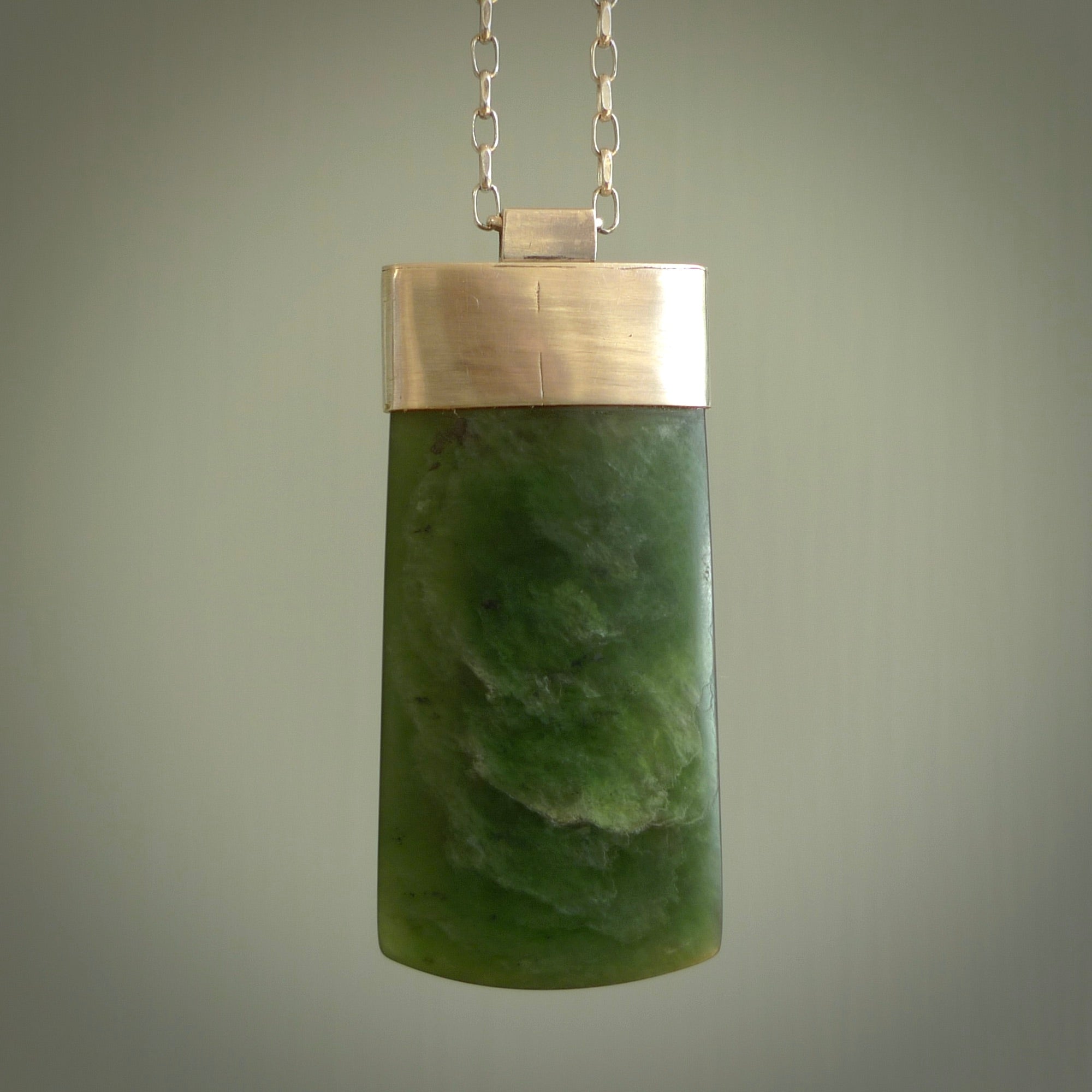 This picture shows a hand carved jade toki, drop pendant with sterling silver cap and chain. The jade is a very dark green with a shimmer in the stone. It is suspended from a sterling silver clasp and we supply a sterling silver chain. Delivery is free worldwide.