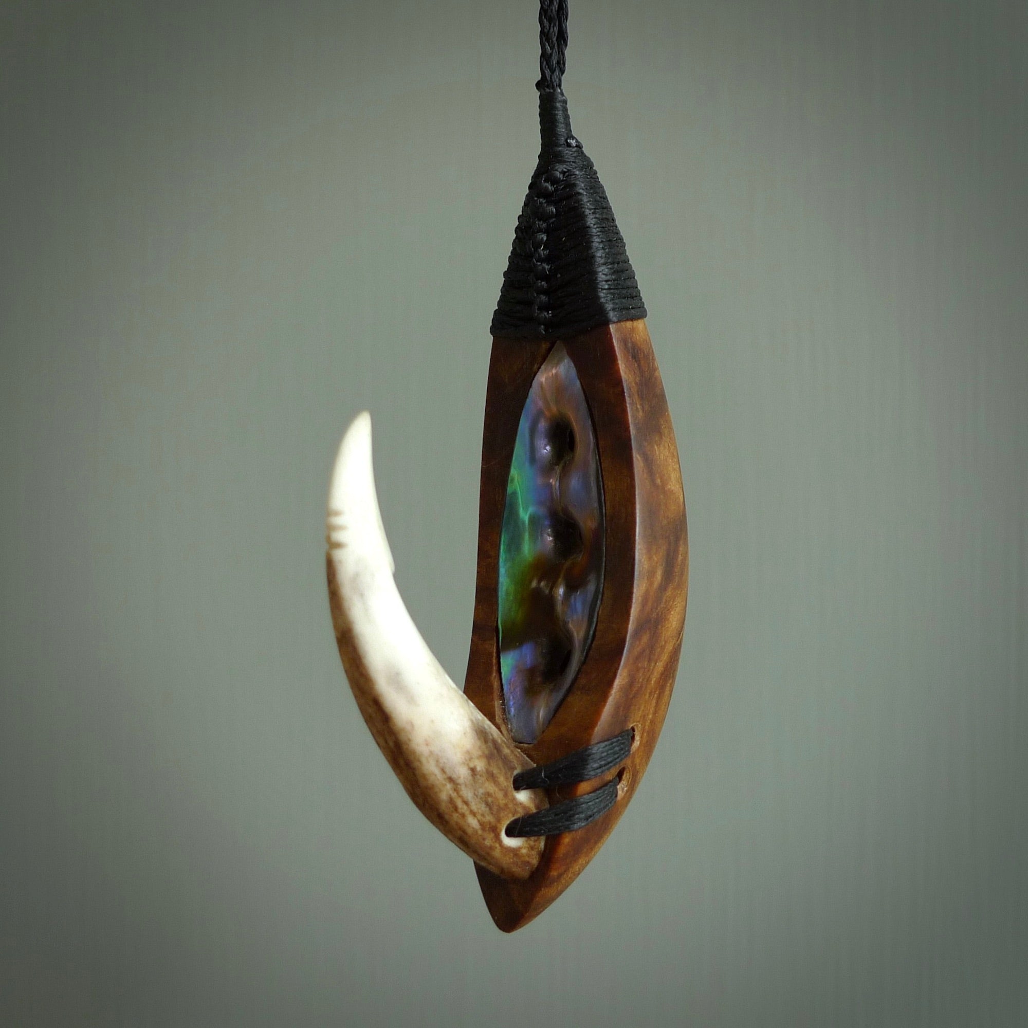 This picture shows a large matau, hook called a pā kahawai. It is carved from deer antler bone, wood, and paua shell. One only, free shipping worldwide. Provided with an adjustable black cord. Stunning work of Art to Wear by Fumio Noguchi.