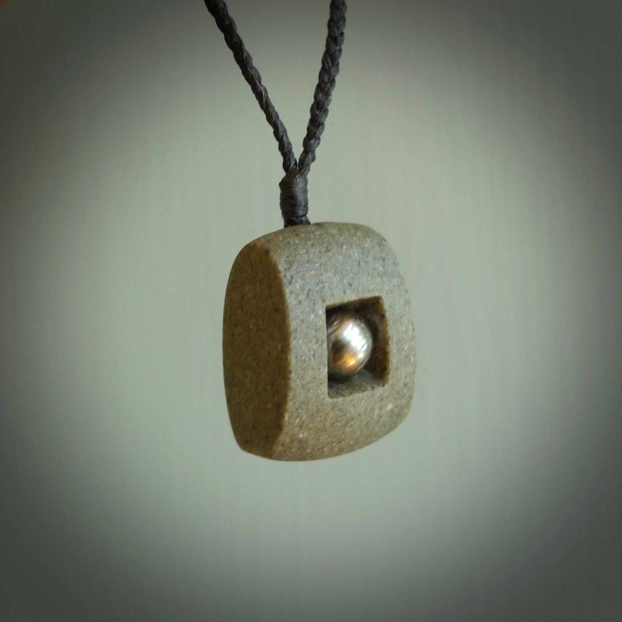 Greywacke stone pendant with Black Pearl insert. Hand carved by Rhys Hall for NZ Pacific. Handmade contemporary jewellery for sale online.