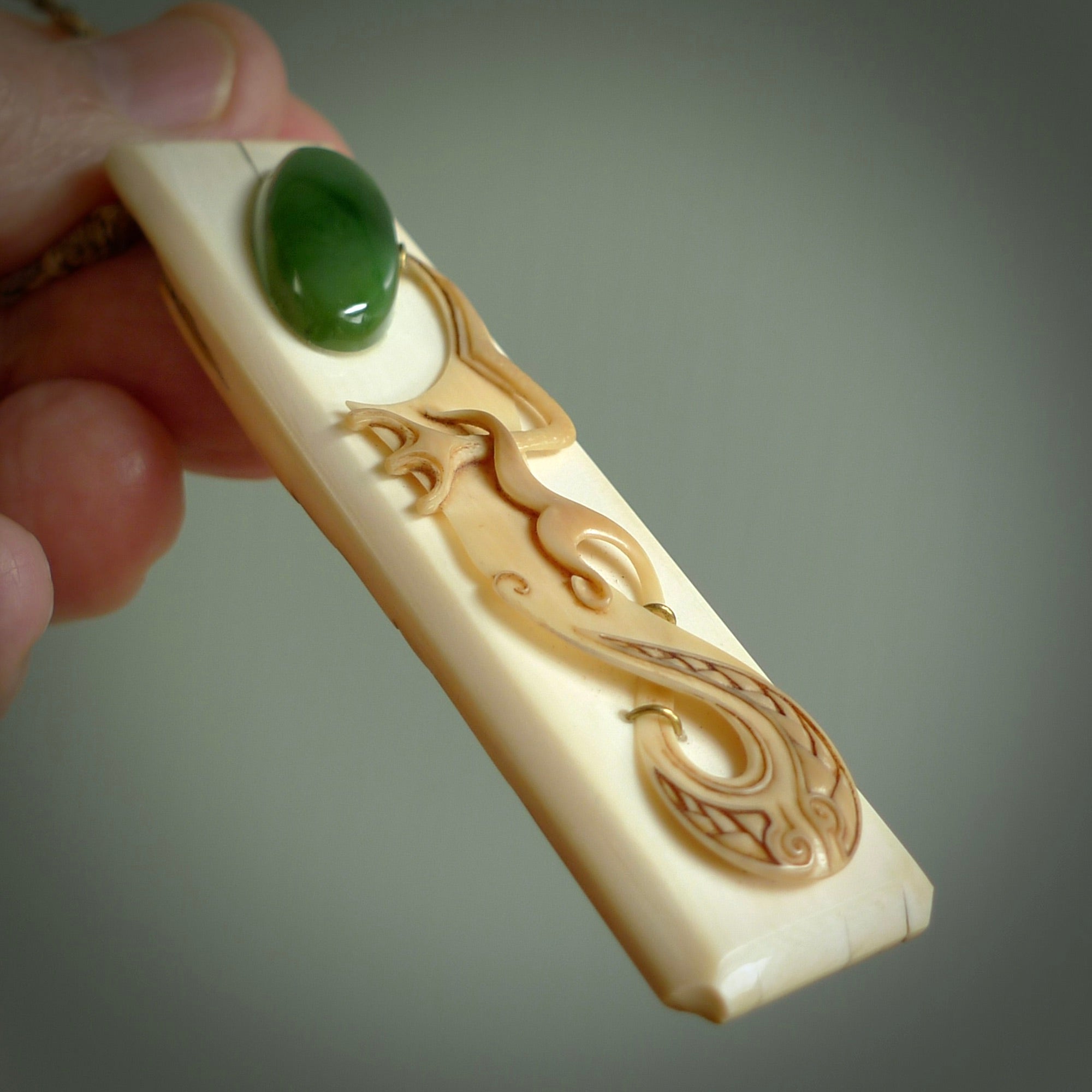 A beautiful, large toki with manaia pendant handmade from woolly mammoth tusk with Jade insert by Sami. Hand carved mammoth tusk toki manaia pendant, provided with an adjustable tan cord. Manaia head earring.