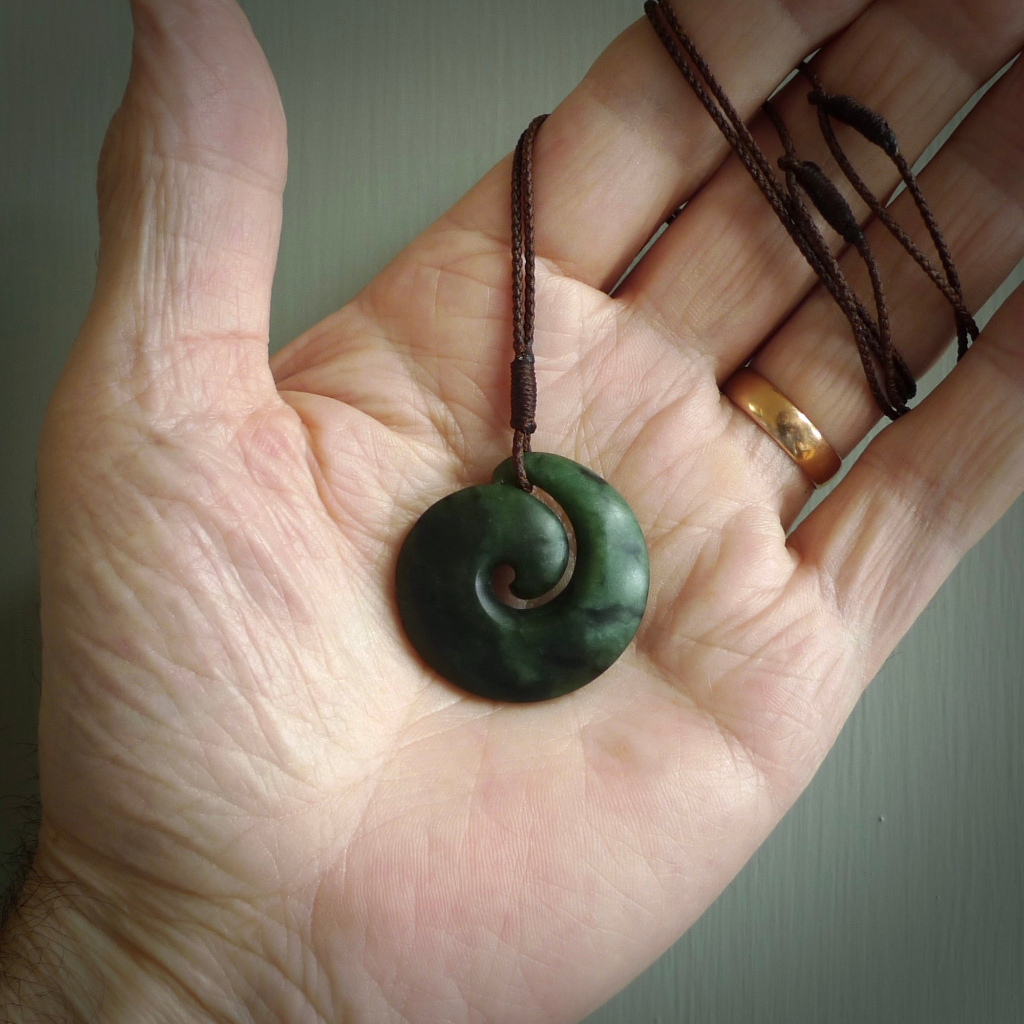 This picture shows a koru pendant, hand carved from New Zealand jade. We will provide this with an adjustable plaited cord. This has been hand carved by Kyohei Noguchi. One only pendant, shipped to you with express courier.