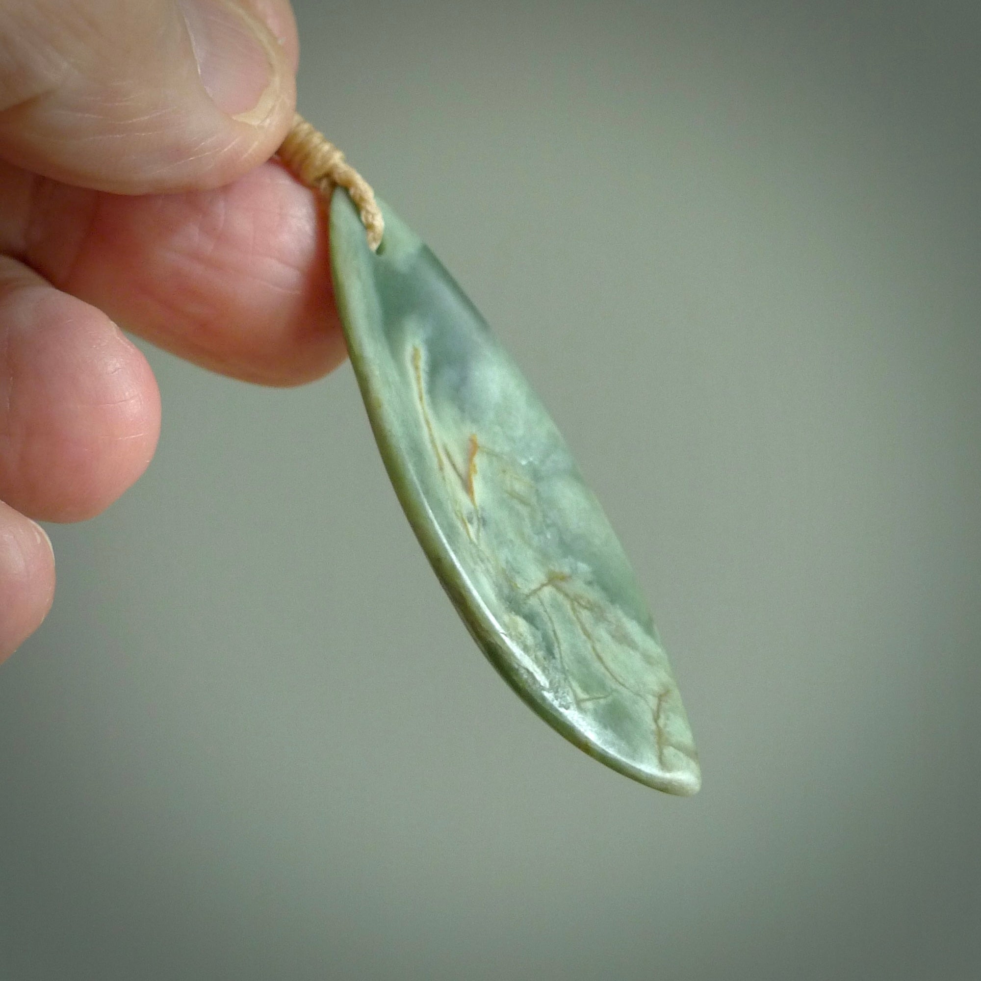 This is a lovely New Zealand Jade, pounamu drop pendant. Hand carved for us by Ric Moor. It is bound with an adjustable beige coloured cord which is length adjustable. Free worldwide shipping.