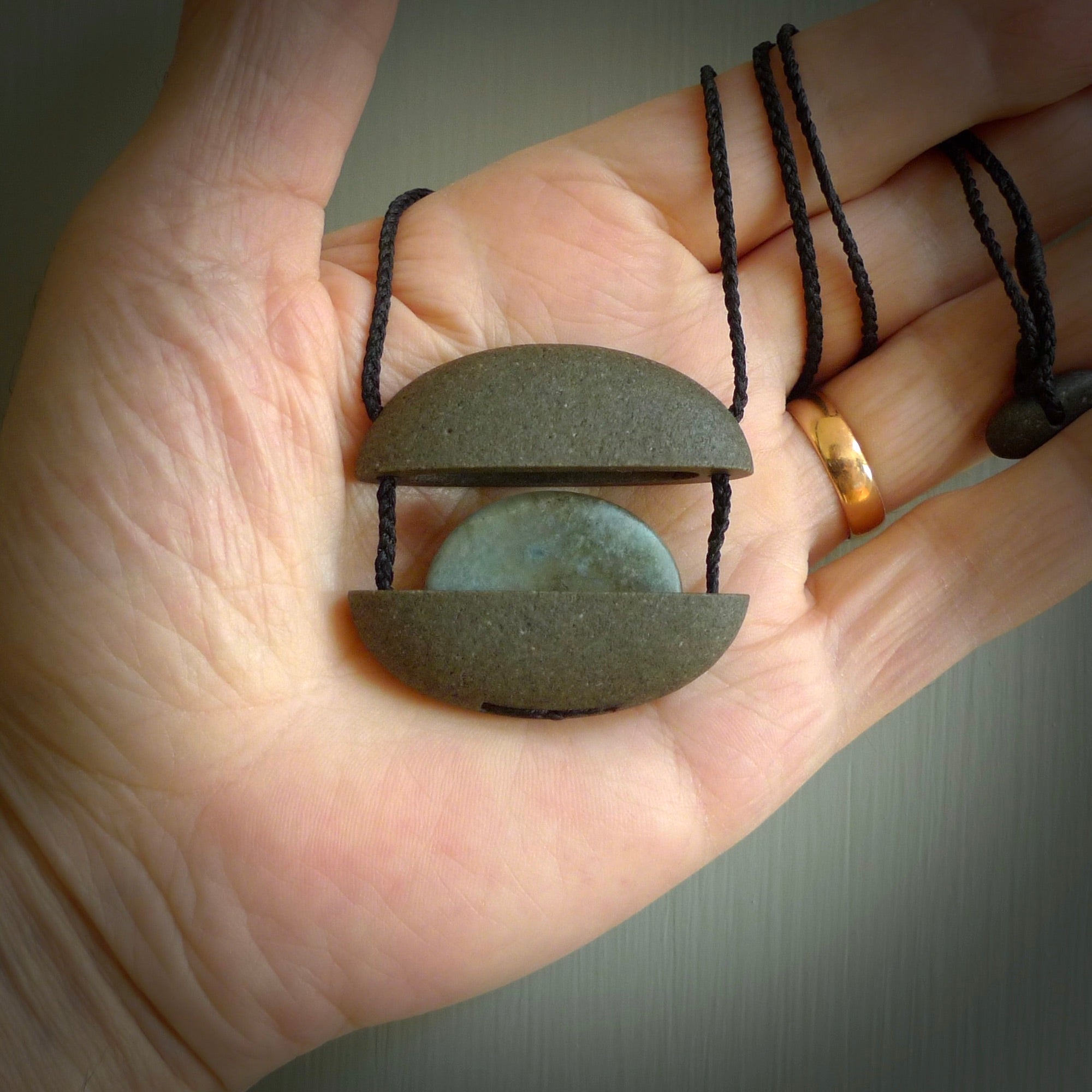 Greywacke stone pendant with Aotea Stone insert. Hand carved by Rhys Hall for NZ Pacific. Handmade contemporary jewellery for sale online.