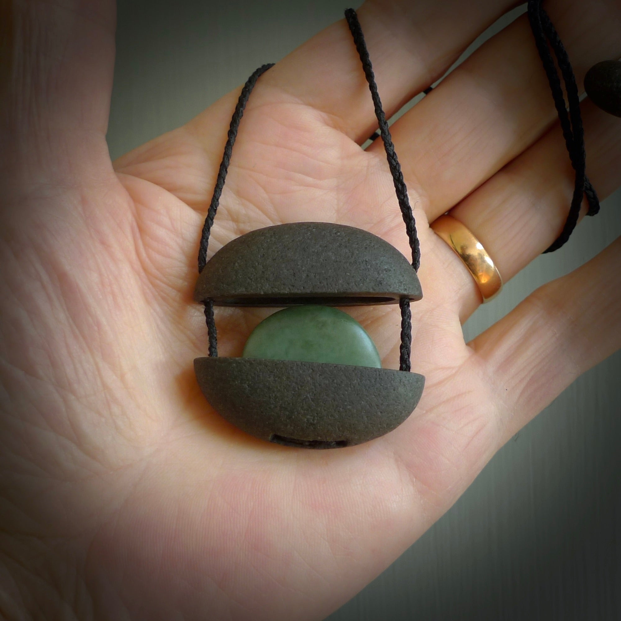 Greywacke stone pendant with New Zealand Inanga Pounamu insert. Hand carved by Rhys Hall for NZ Pacific. Handmade contemporary jewellery for sale online.