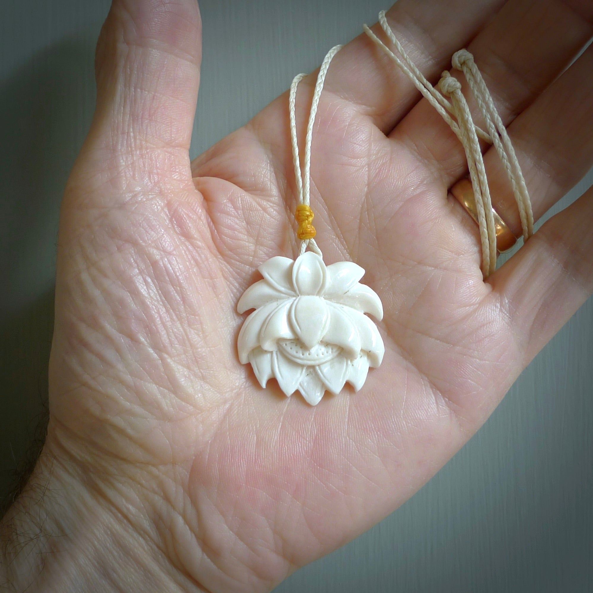 This is a hand carved lotus flower pendant. It is made from bone. This is a medium sized necklace and is a very unique pendant and is a wonderful necklace to wear. Hand carved bone lotus flower pendant with adjustable cord.