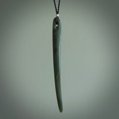 This picture shows a hand carved Pounamu jade beak drop pendant with adjustable cord. The jade is a very dark green with shimmering blue tones in the stone. It is suspended from a adjustable cord. Delivery is free worldwide.