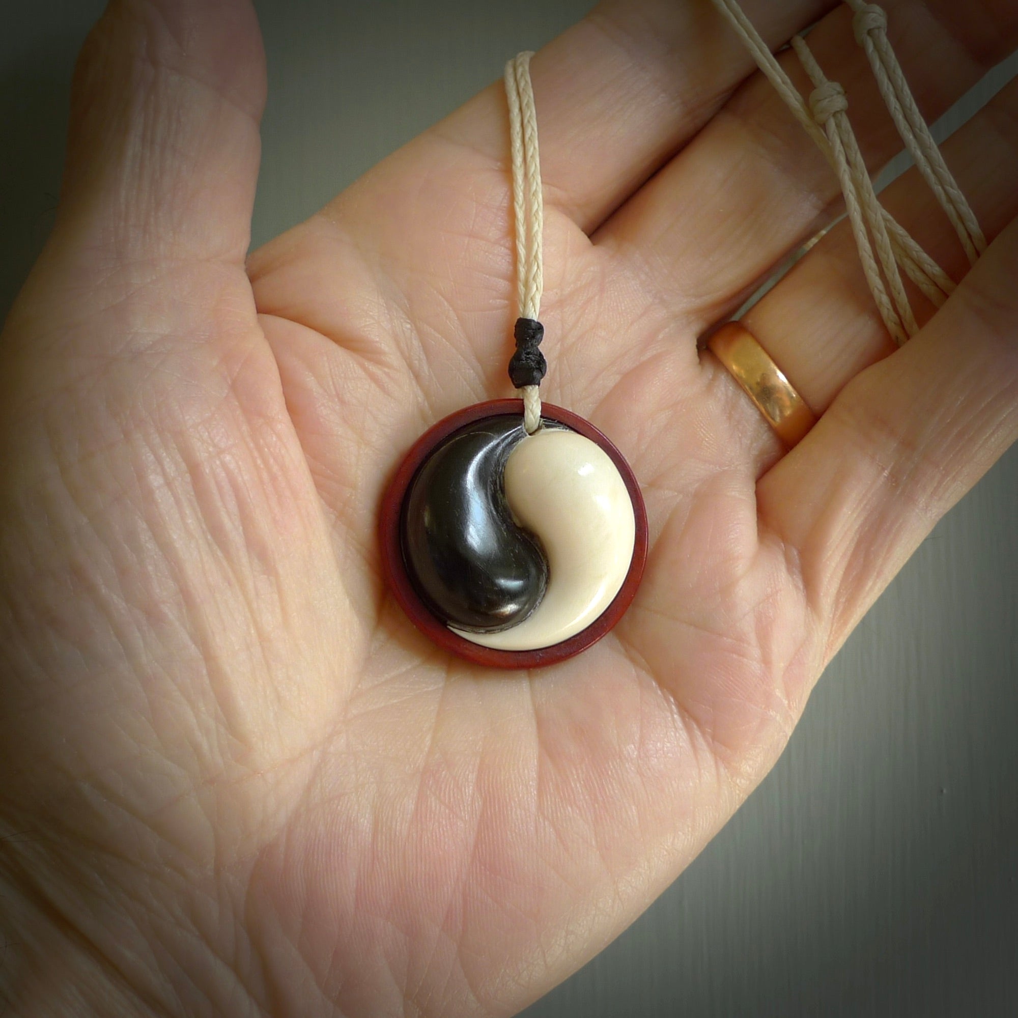 A hand carved and intricate yin and yang pendant made for us by Yuri Terenyi. This is a beautiful little piece and is emblematic of the well known and loved YIN & YANG design. It is carved from bone and buffalo horn. We have two available - one is suspended from an Ice White cord with a black floret and the other is suspended from an Black cord with Ice white floret. The necklace is adjustable.