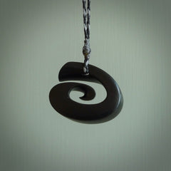 A hand carved medium sized Black Jade Koru necklace. The cord is a black colour and is a fixed length . A medium sized hand made hook necklace by New Zealand artist Kerry Thompson. One off work of art to wear.