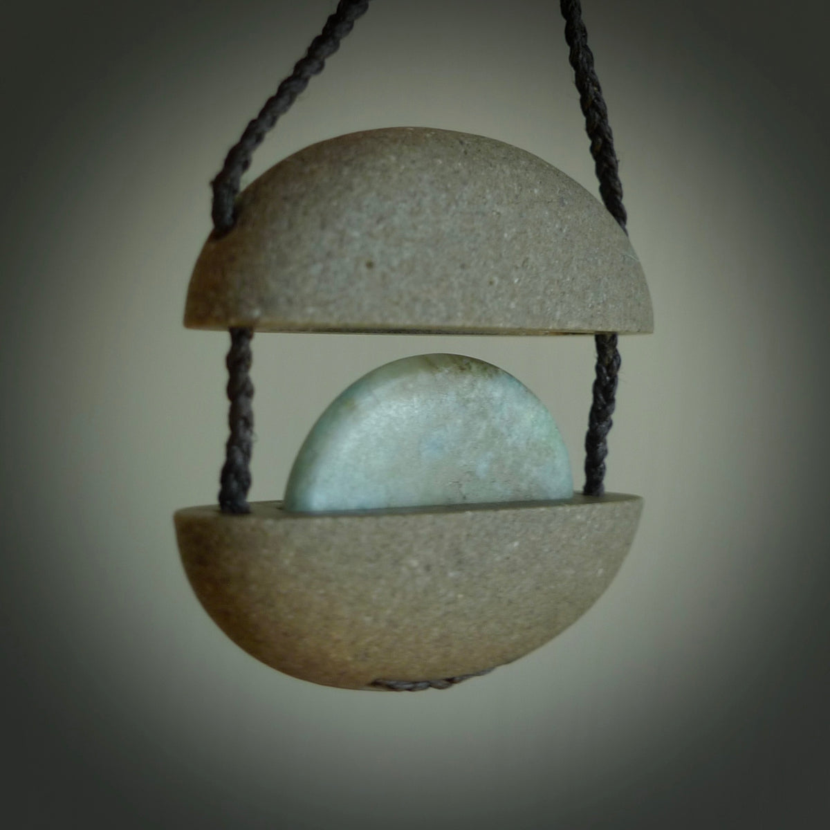 Greywacke stone pendant with Aotea Stone insert. Hand carved by Rhys Hall for NZ Pacific. Handmade contemporary jewellery for sale online.