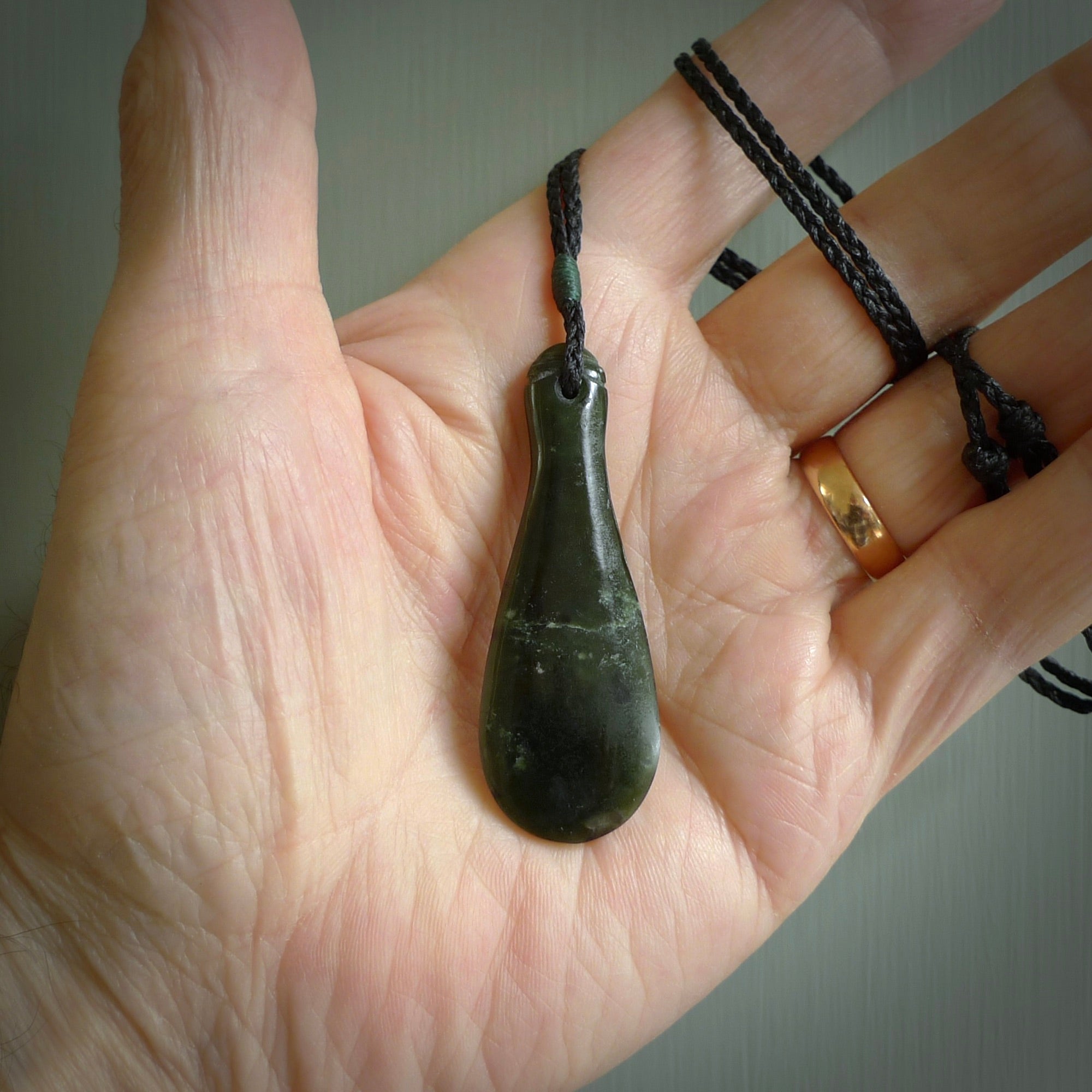 This is a sleek and slender hand carved New Zealand Jade mere pendant. The stone is a very beautiful green and the cord is either black or green and is adjustable. The pendant has a light polish and just glows. Provided in a woven kete pouch.