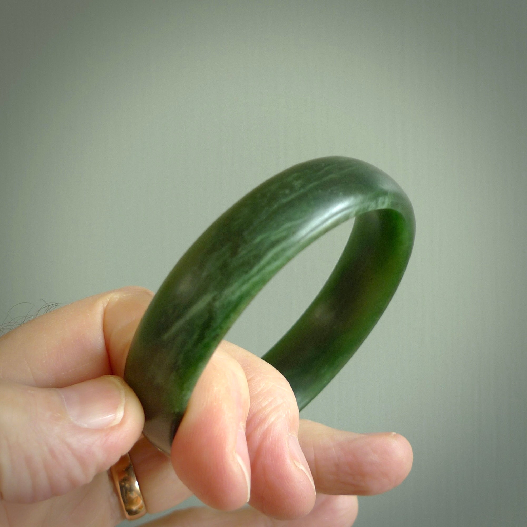 Hand carved New Zealand Jade bangle with matte finish, by Ric Moor. This is a spectacular one off, bracelet hand made in New Zealand from gorgeous Jade. Unique art to wear, delivered in a woven kete pouch. Real New Zealand Jade. Outstanding craftsmanship by New Zealand Master Carver Ric Moor.