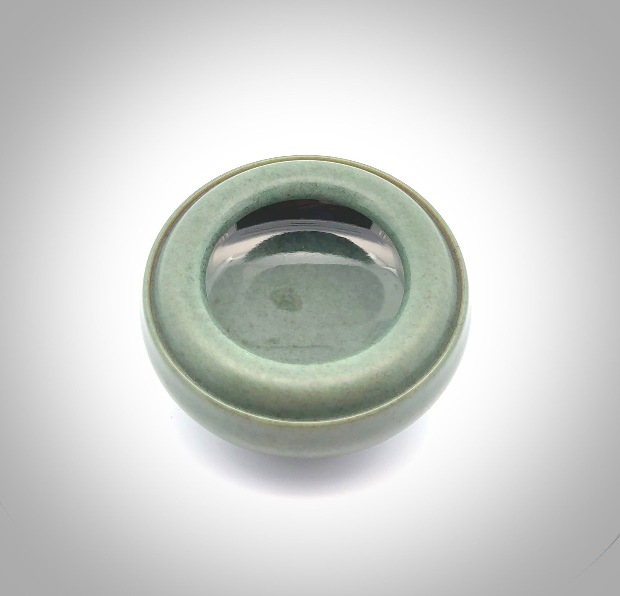 This photo shows a hand carved, Wyoming 'Sage' Nephrite Jade bowl sculpture. This 3.5 inch bowl carved from extremely fine-grained Sage. With Wyoming Black Jade and Sterling Silver, high domed centre grip. This hand crafted work of art was hand made by award winning New Zealand carver Donn Salt.