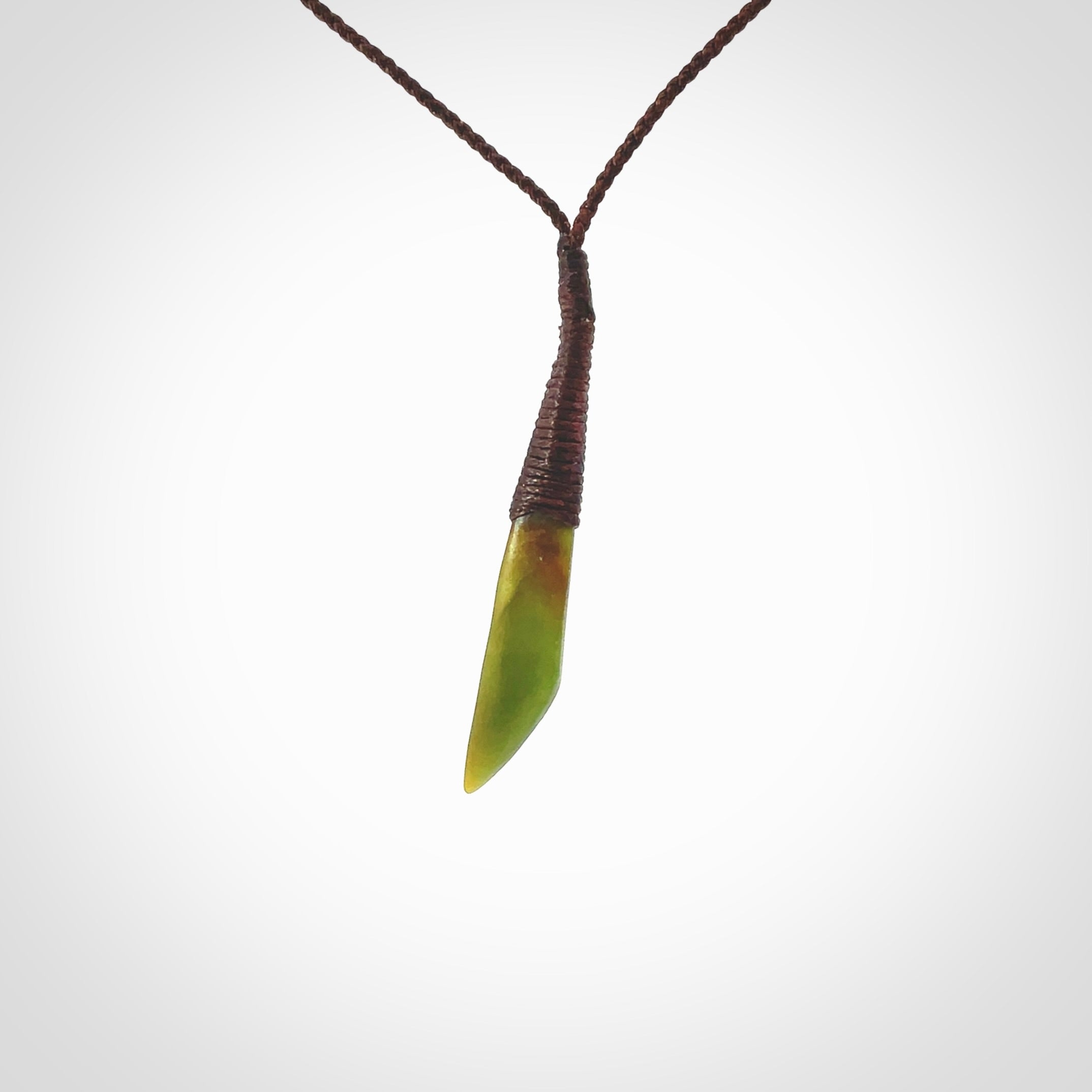 A lovely medium sized New Zealand jade drop pendant. This piece is made from a light, orange and green jade and is a wonderful semi-translucent green colour. Carved by Ric Moor for NZ Pacific and delivered worldwide. Provided with adjustable brown cord.