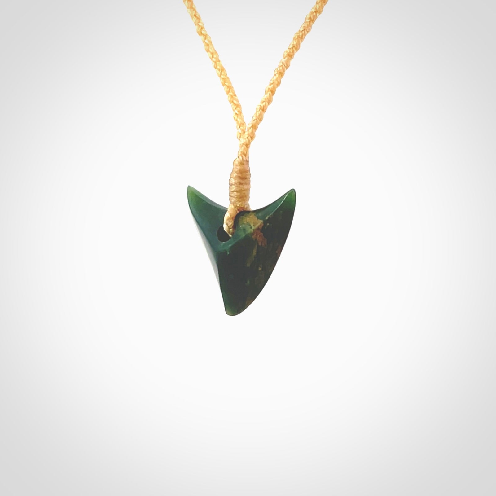 This is a lovely New Zealand Jade, pounamu drop pendant. Hand carved for us by Ric Moor. It is bound with an adjustable beige coloured cord which is length adjustable. Free worldwide shipping. The light reveals the internal structure and colour of the stone beautifully.