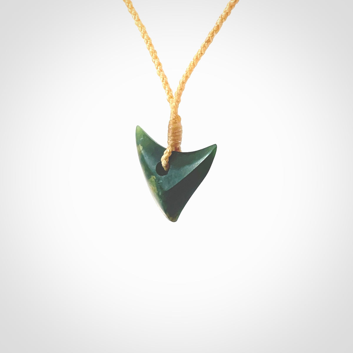 This is a lovely New Zealand Jade, pounamu drop pendant. Hand carved for us by Ric Moor. It is bound with an adjustable beige coloured cord which is length adjustable. Free worldwide shipping. The light reveals the internal structure and colour of the stone beautifully.