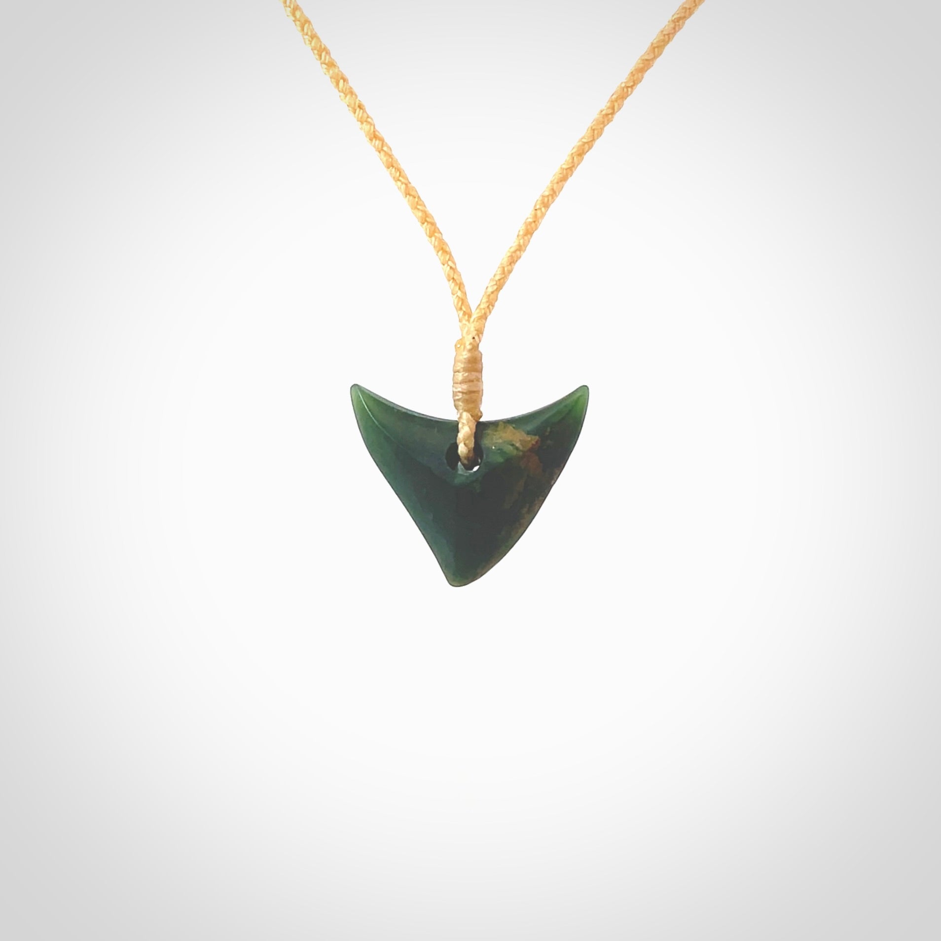 This is a lovely New Zealand Jade, pounamu drop pendant. Hand carved for us by Ric Moor. It is bound with an adjustable beige coloured cord which is length adjustable. Free worldwide shipping. The light reveals the internal structure and colour of the stone beautifully.