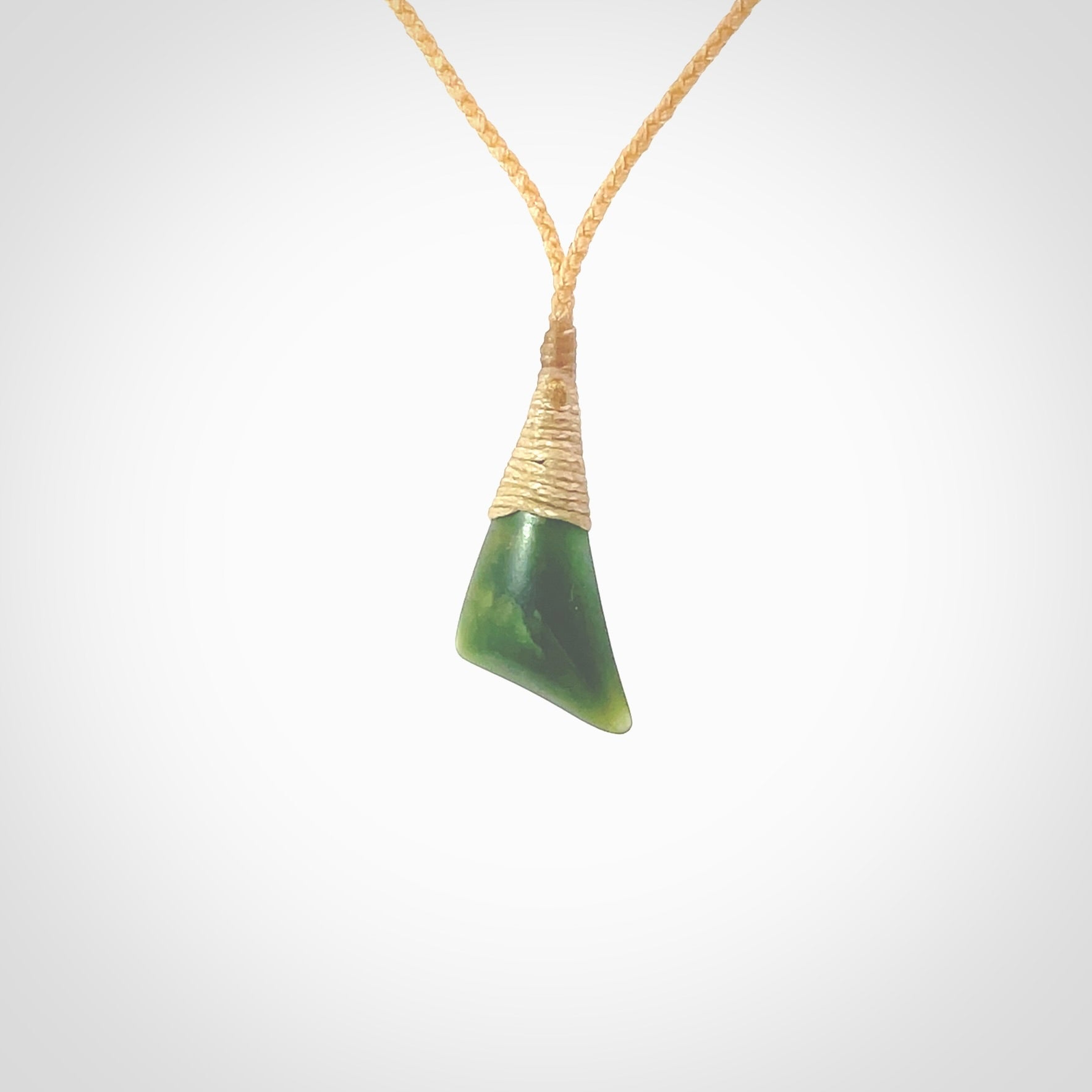 A lovely small sized New Zealand jade drop pendant. This piece is made from a dark, green jade and has a wonderful light green semi-translucent colour also. Carved by Ric Moor for NZ Pacific and delivered worldwide. Delivered with adjustable beige cord.