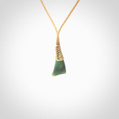 A lovely small sized New Zealand jade drop pendant. This piece is made from a dark, green jade and has a wonderful light green semi-translucent colour also. Carved by Ric Moor for NZ Pacific and delivered worldwide. Delivered with adjustable beige cord.